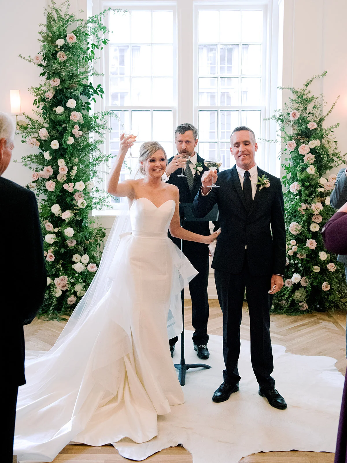 Champagne toast during wedding ceremony with blush and ivory floral installation in the Noelle. Nashville wedding floral design.