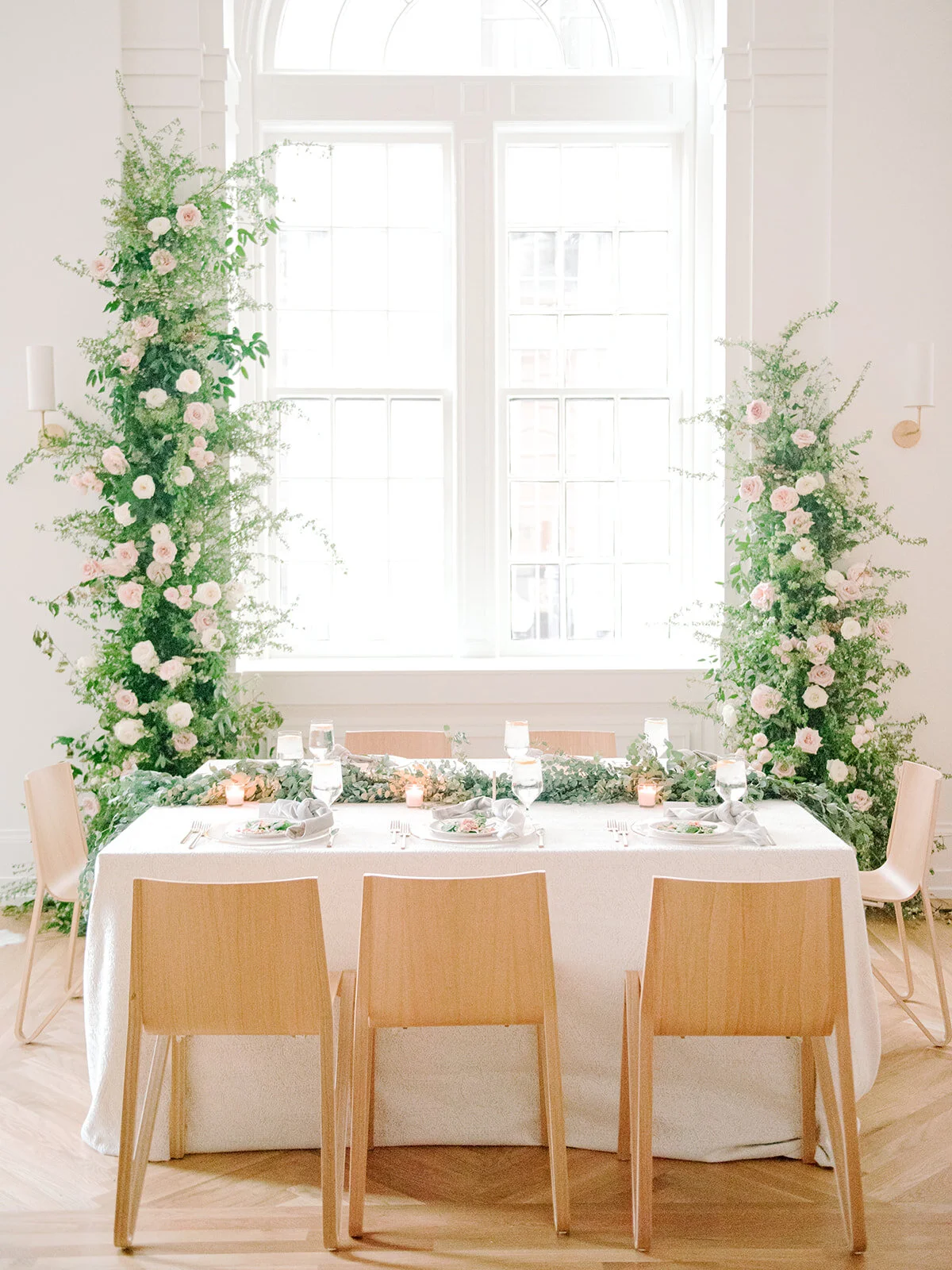 Sweetheart table with asymmetrical floral installation growing up either side of the windows in the Noelle. Nashville Wedding Florist.