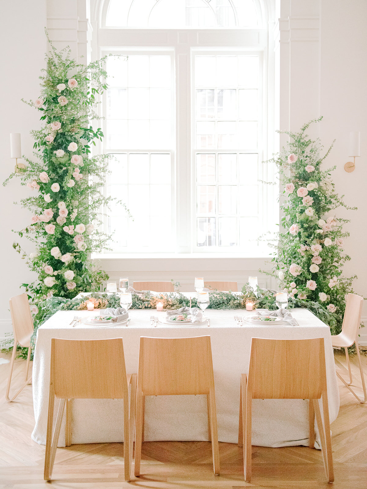Sweetheart table with asymmetrical floral installation growing up either side of the windows in the Noelle. Nashville Wedding Florist.