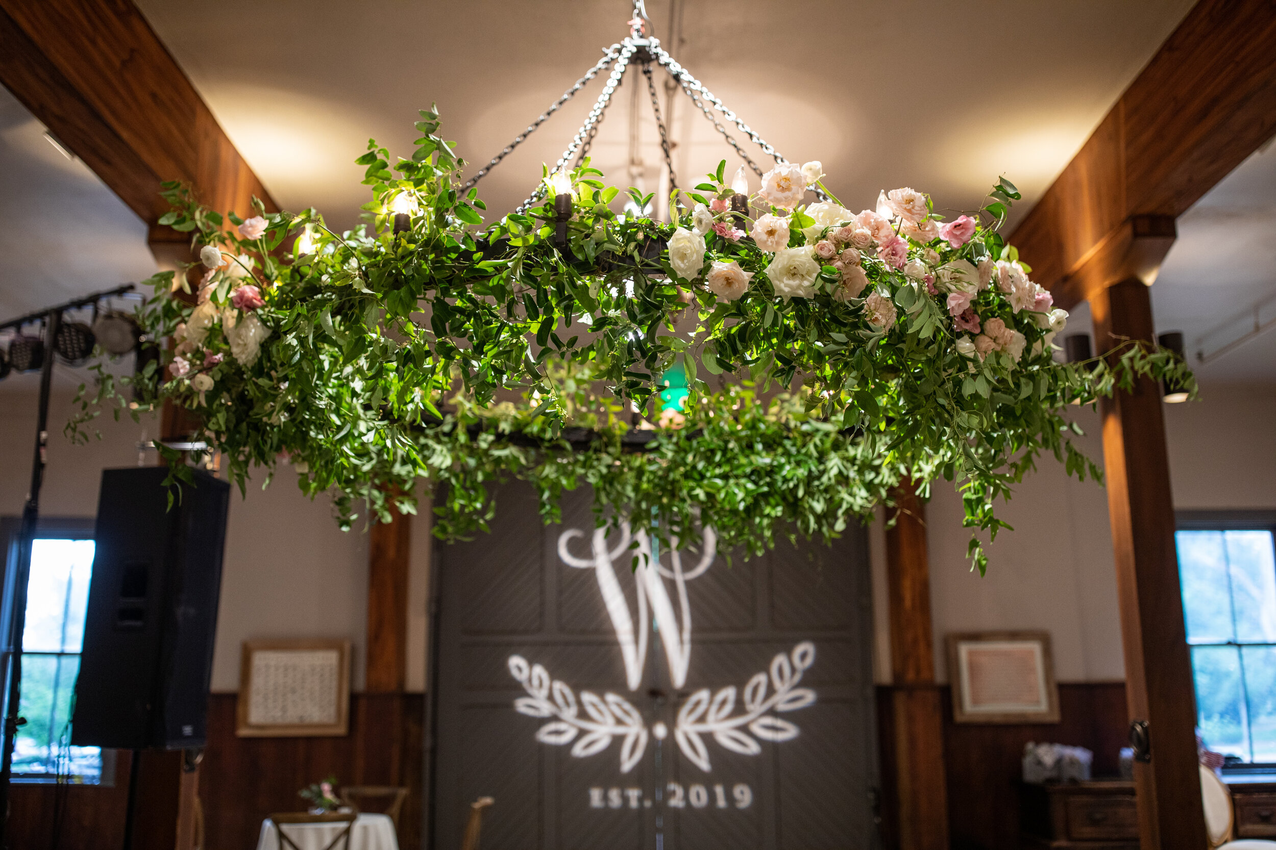 Oversized floral wreath installation over the dance floor with lush vines and greenery with blush and white flowers. Nashville event and wedding florist at Belle Meade Plantation.