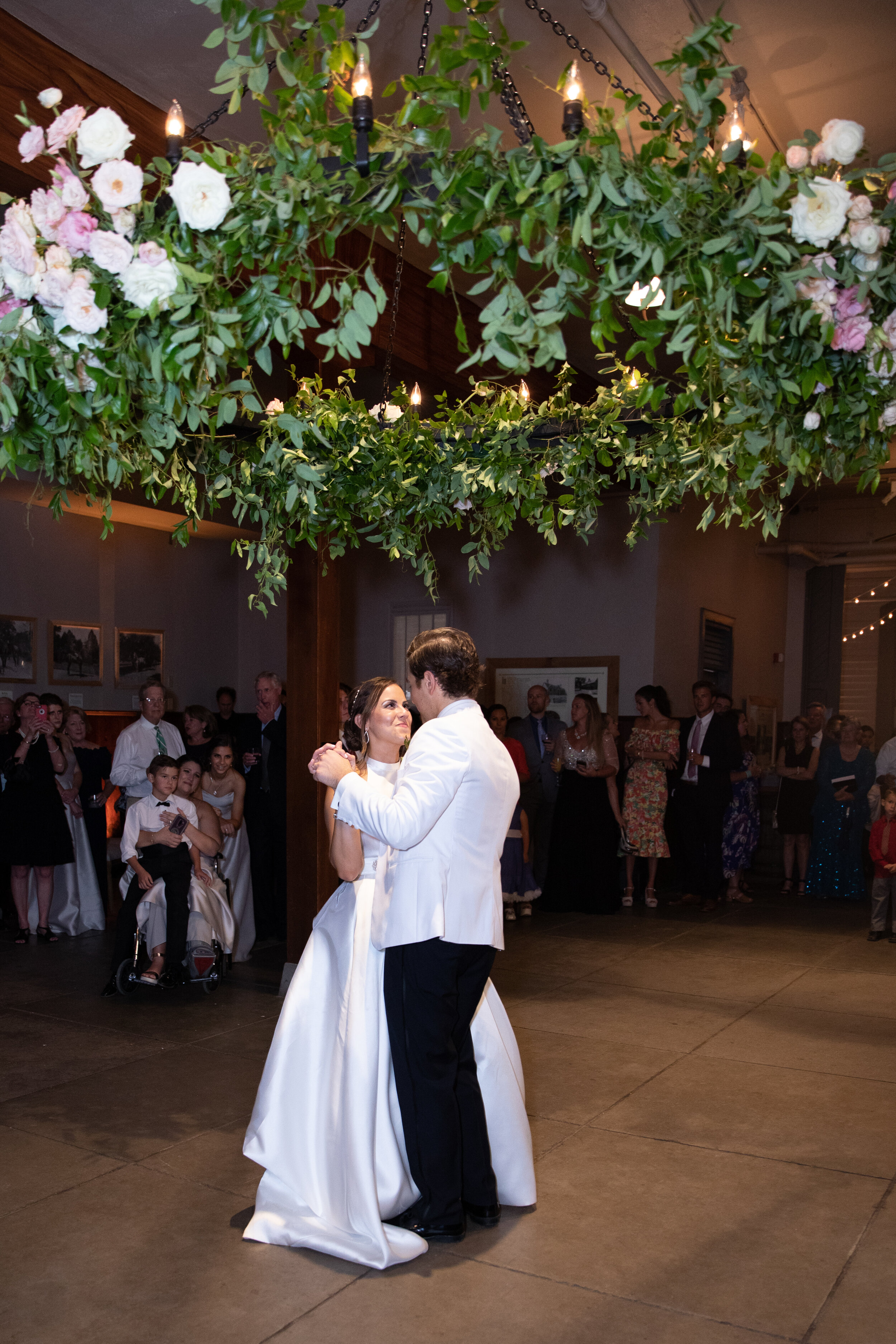 Oversized floral wreath installation over the dance floor with lush vines and greenery with blush and white flowers. Nashville event and wedding florist at Belle Meade Plantation.