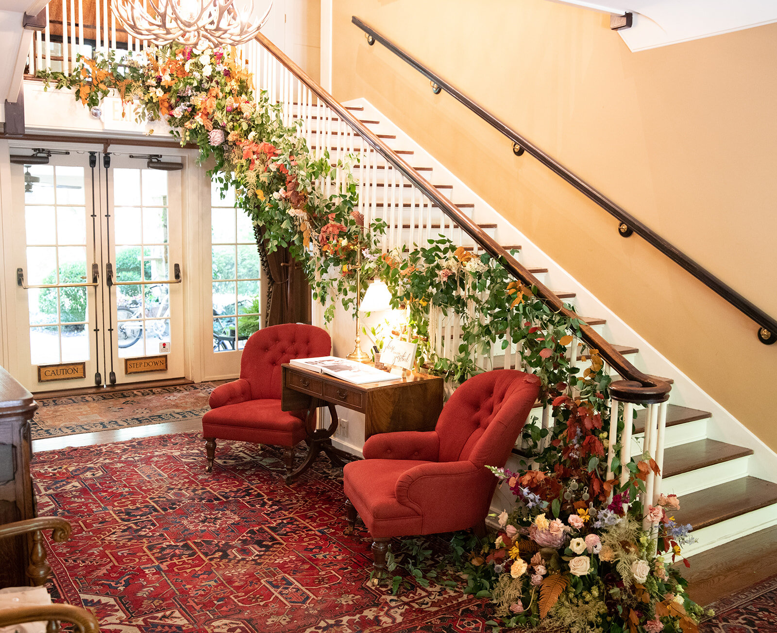 Early fall wedding floral design at RT Lodge. Lush, untamed installation growing up the staircase with wildflowers, protea, fruiting branches, ranunculus, garden roses, and dried textures.