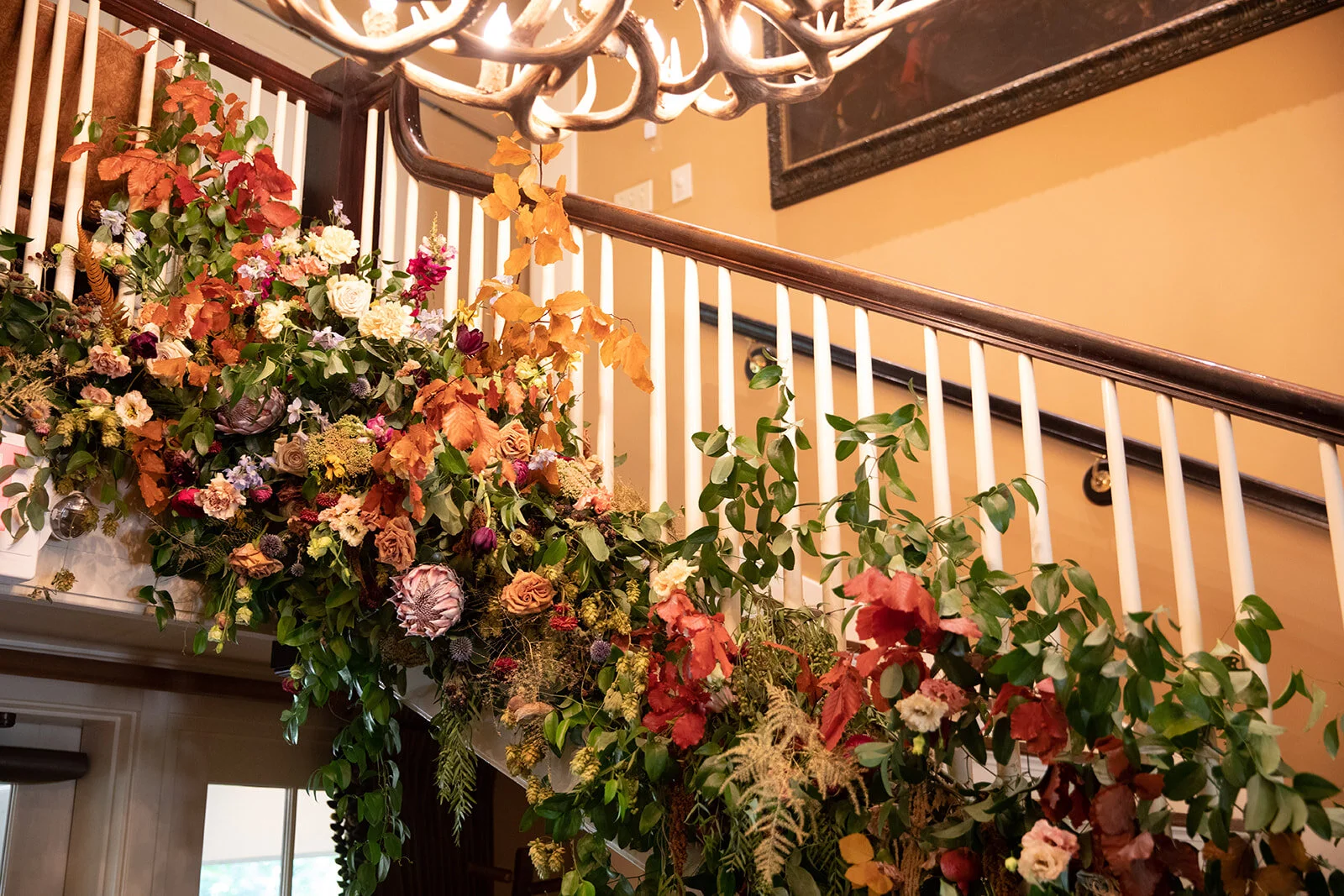 Early fall wedding floral design at RT Lodge. Lush, untamed installation growing up the staircase with wildflowers, protea, fruiting branches, ranunculus, garden roses, and dried textures.