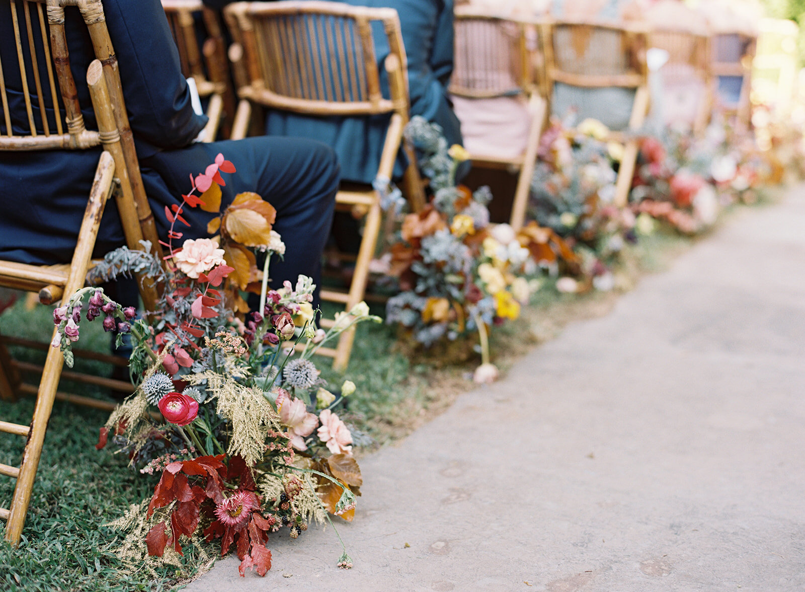 Colorful wildflower aisle markers growing by each chair for the wedding ceremony, using thistles, copper beech, delphinium, snapdragons, ranunculus, dried elements, and brown lisianthus. Nashville and RT Lodge florist.