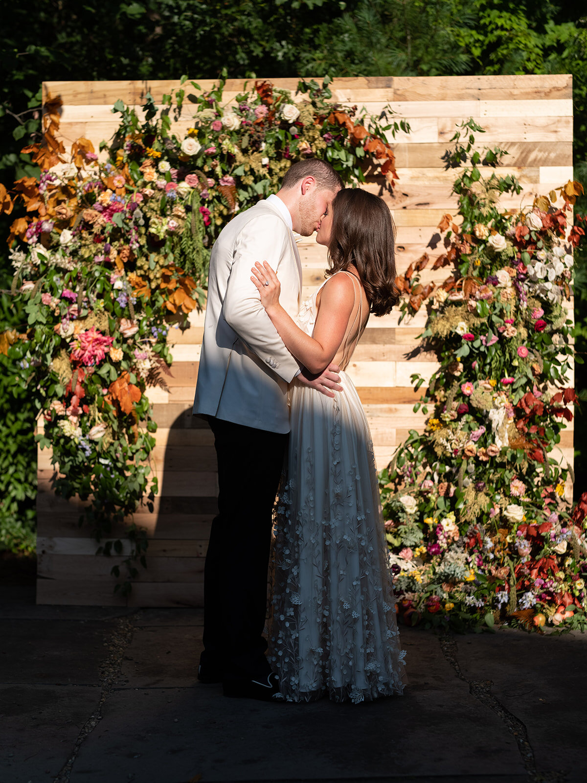 Reclaimed wood wall built by the father of the bride with lush, garden-inspired floral installation, using wildflowers, hops, fruiting branches, copper beech, ranunculus, garden roses, and tulips. RT Lodge wedding ceremony flowers.
