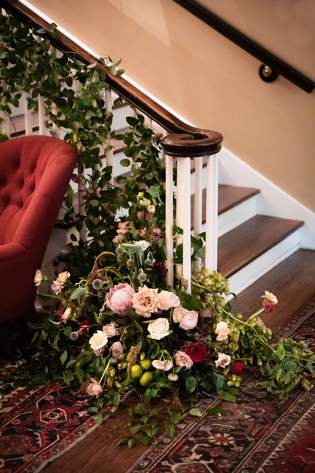 Early fall wedding floral design at RT Lodge. Lush, untamed installation growing up the staircase with wildflowers, protea, fruiting branches, ranunculus, garden roses, and dried textures.