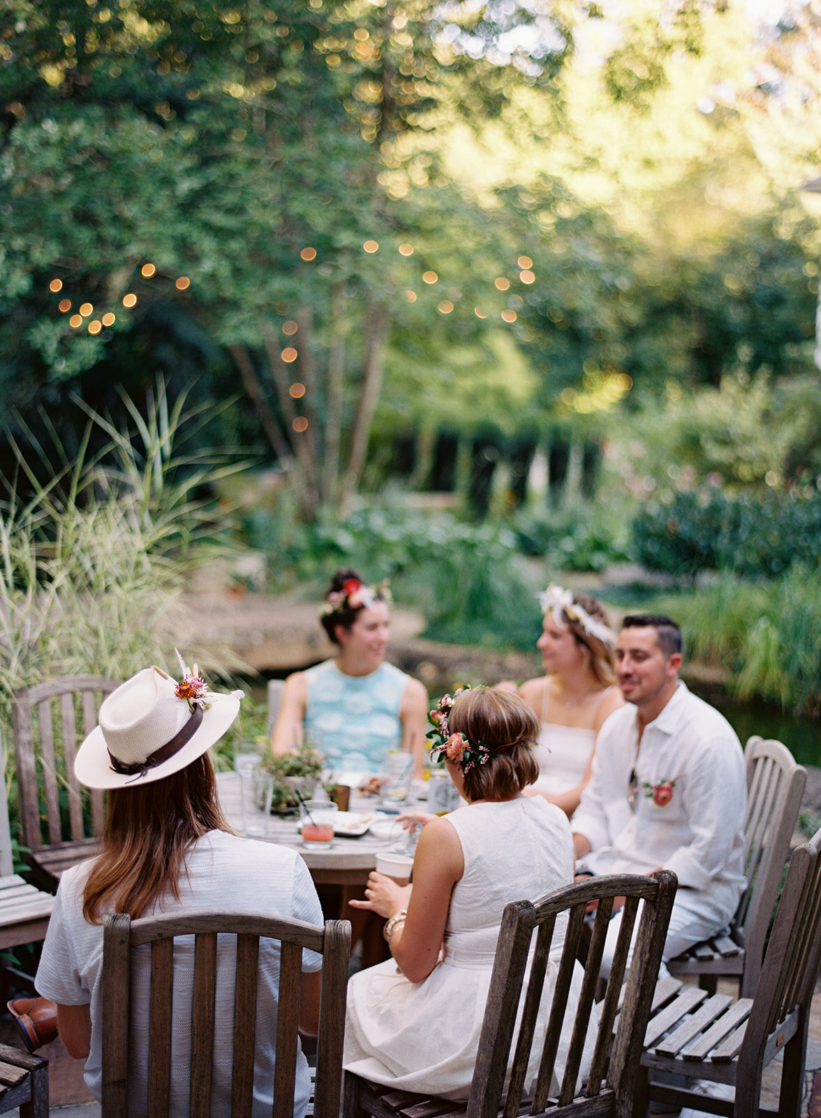 White linen welcome dinner with flower crown for every guest. Wildflower crown booth by Rosemary & Finch, RT Lodge and Nashville luxury wedding florist.