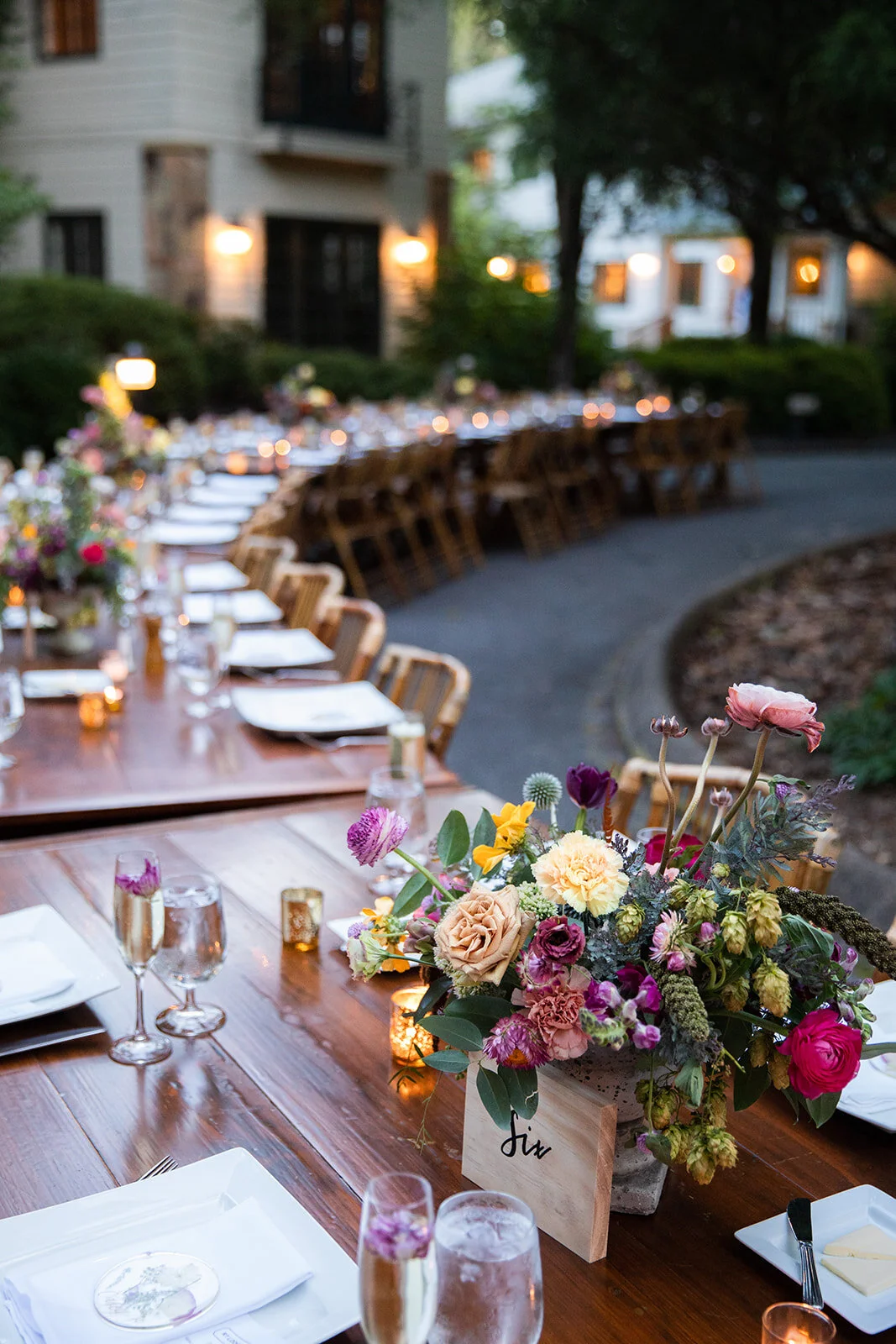 Garden urn wildflower centerpiece with deep red garden roses, dusty pink ranunculus, hops, berries, maroon snapdragon, thistles, golden yellow zinnias, and natural greenery. RT Lodge and Nashville luxury wedding floral designer.