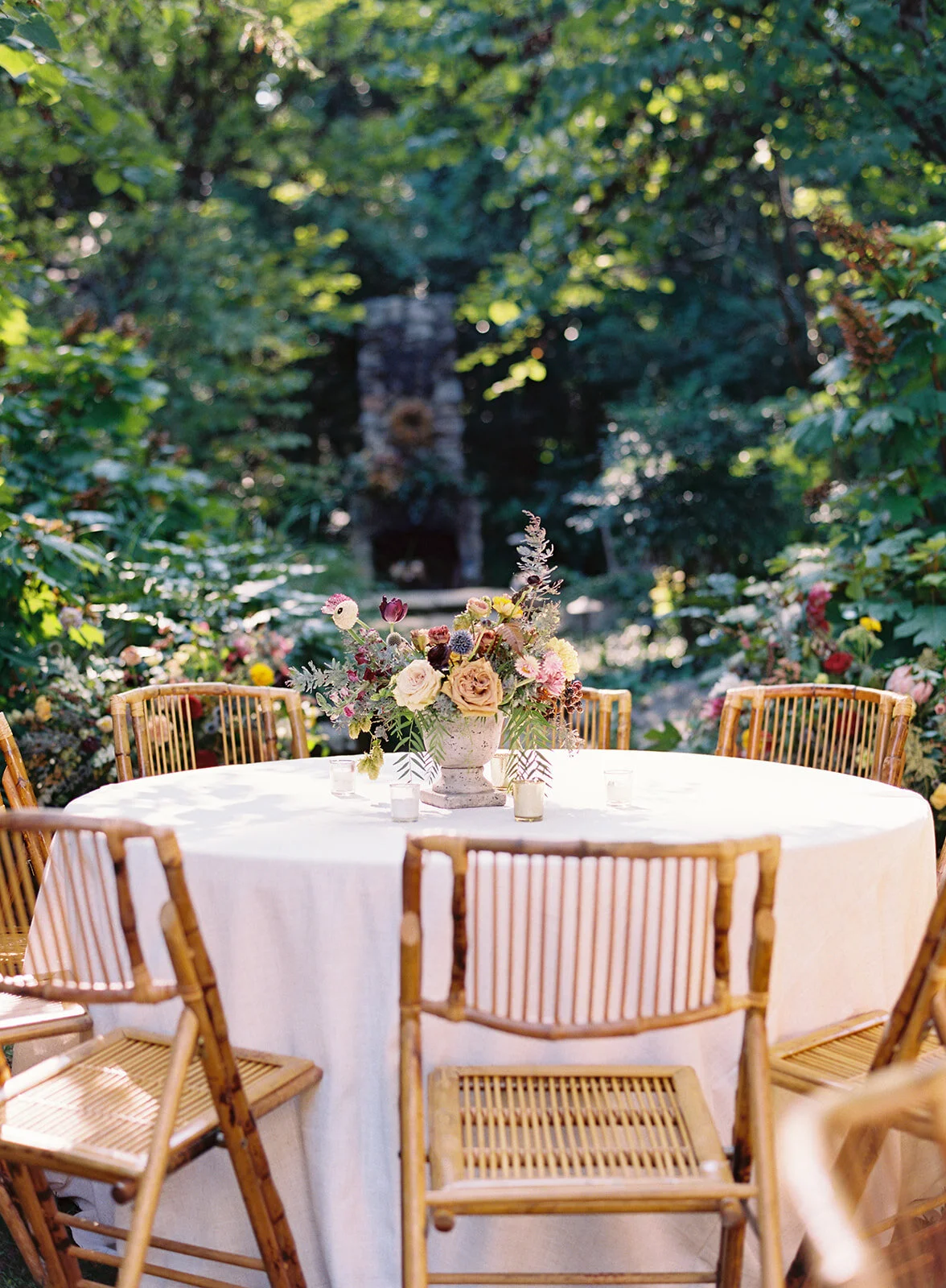 Garden urn wildflower centerpiece with deep red garden roses, dusty pink ranunculus, hops, berries, maroon snapdragon, thistles, golden yellow zinnias, and natural greenery. RT Lodge and Nashville luxury wedding floral designer.
