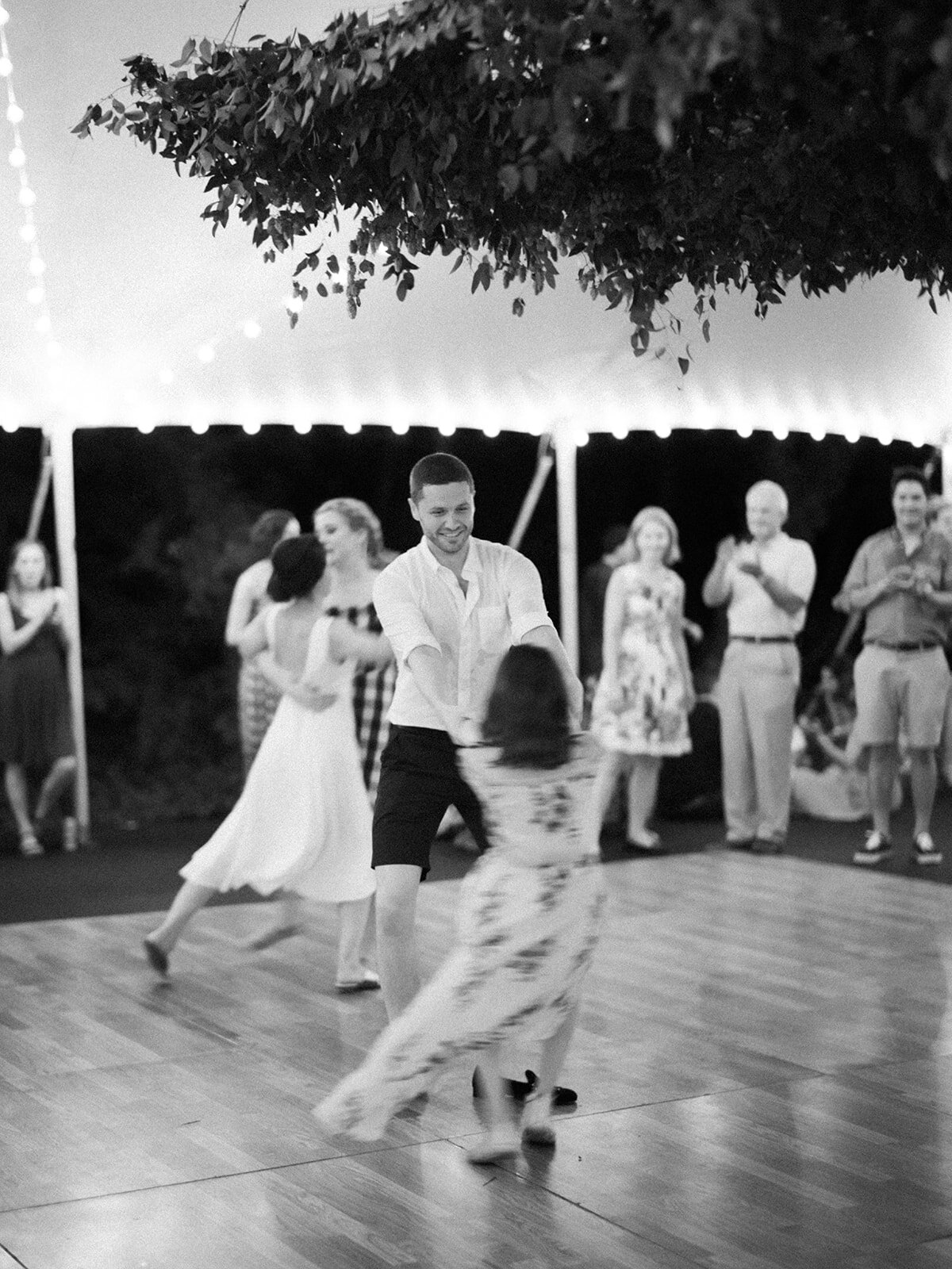 Hanging greenery installation over a square dance for the welcome party. Wedding and event floral design at RT Lodge.