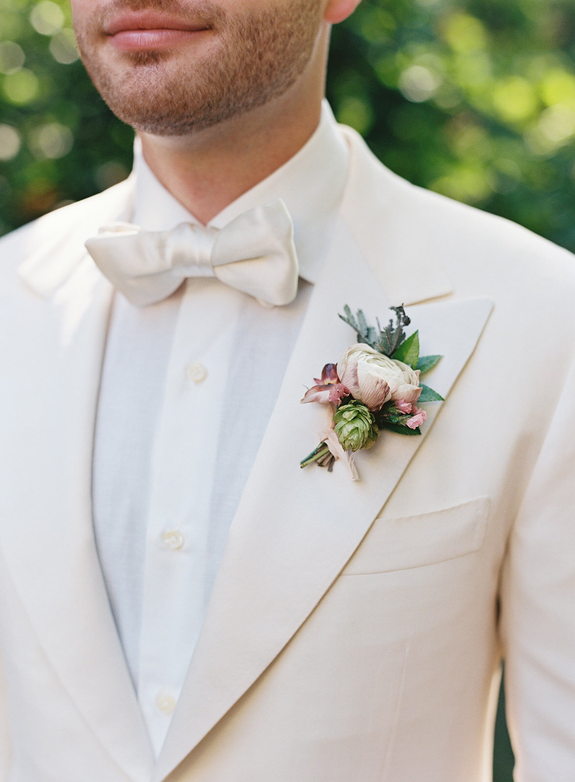 Dusty pink ranunculus groom boutonniere with hops, wildflower textures, and greenery. RT Lodge wedding florist.