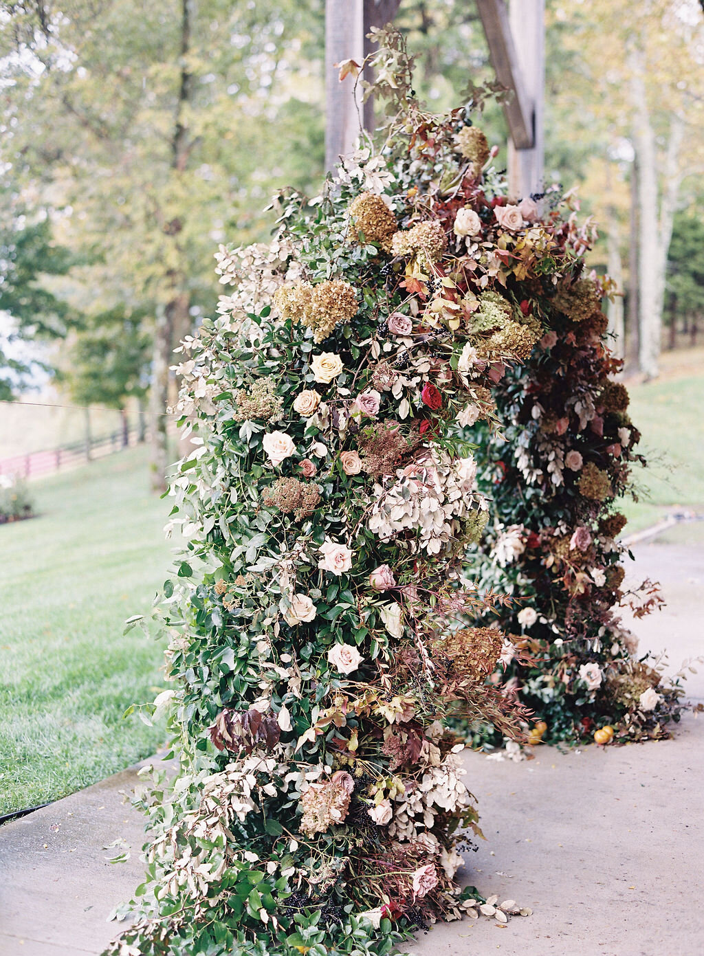 Wild, organic, round floral arch with autumnal color palette and fruit accents. Nashville wedding floral design at Trinity View Farm.