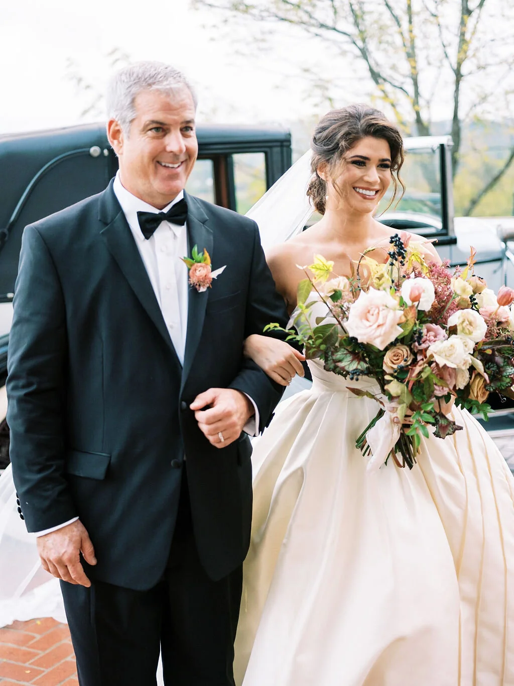 Lush, wild, untamed fall bridal bouquet with a muted autumnal color palette, composed of ligustrum berries, dusty pink ranunculus, tulips, garden roses, fall leaves, begonia leaves, and muted textures. Nashville wedding and corporate event floral de…