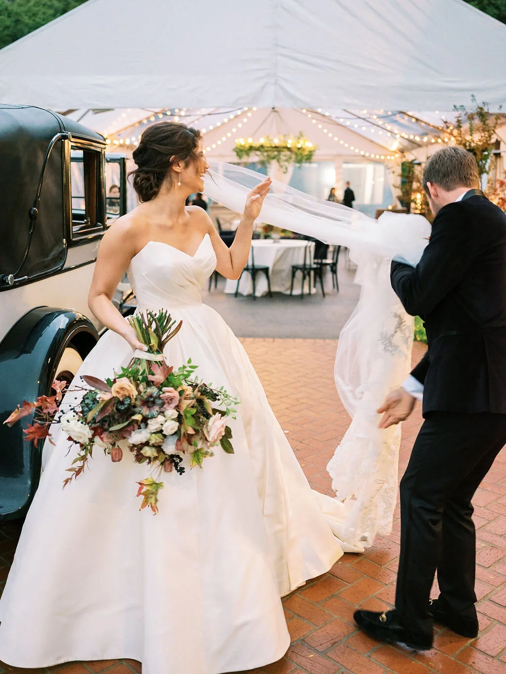 Lush, wild, untamed fall bridal bouquet with a muted autumnal color palette, composed of ligustrum berries, dusty pink ranunculus, tulips, garden roses, fall leaves, begonia leaves, and muted textures. Nashville wedding and corporate event floral de…