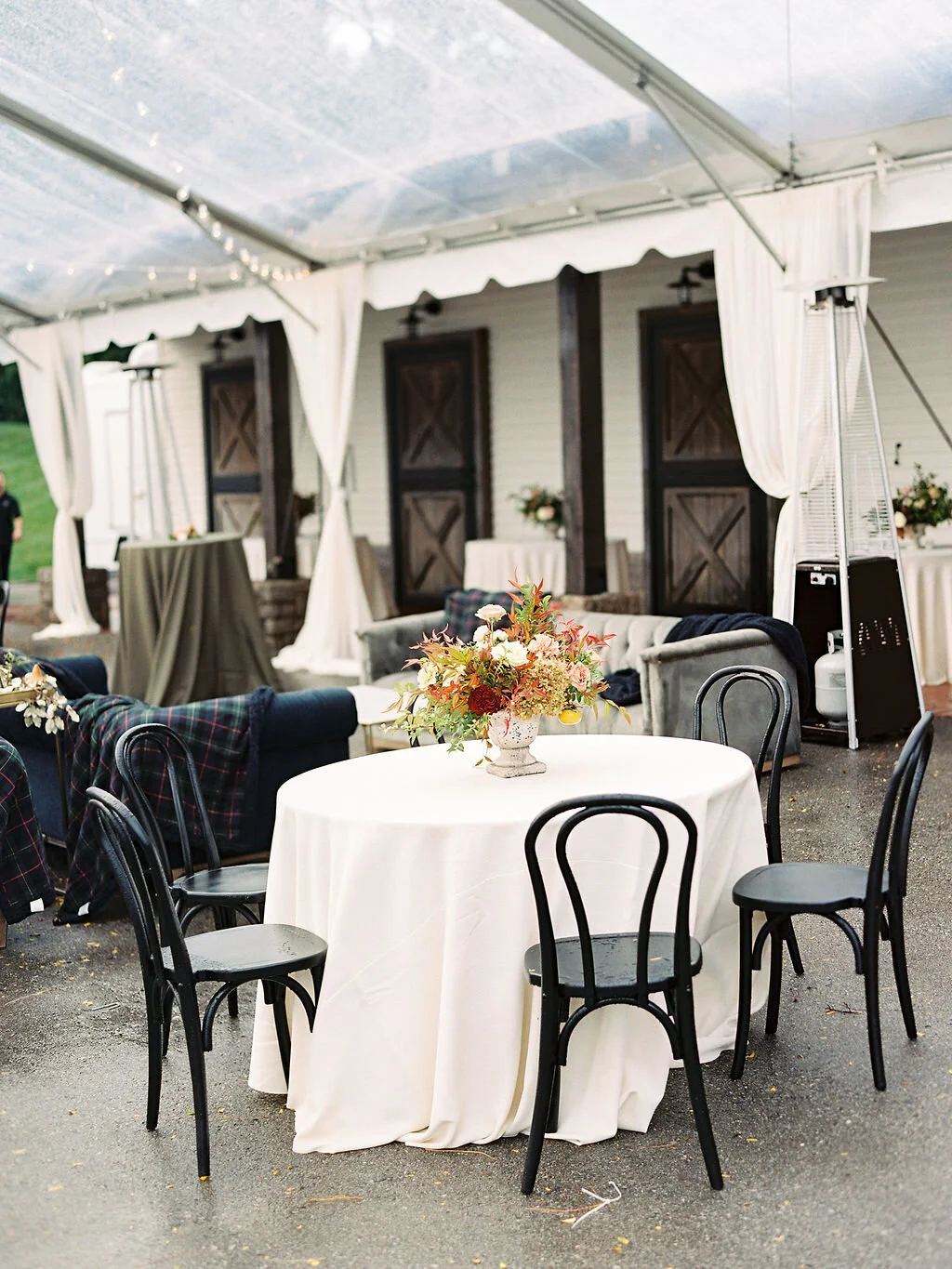 Low European garden urn overflowing with a natural floral arrangement of garden roses, ranunculus, festival bush, fruiting persimmon branches, organic greenery, and fall berries. Centerpiece for a Trinity View Farm wedding by Nashville florist, Rose…