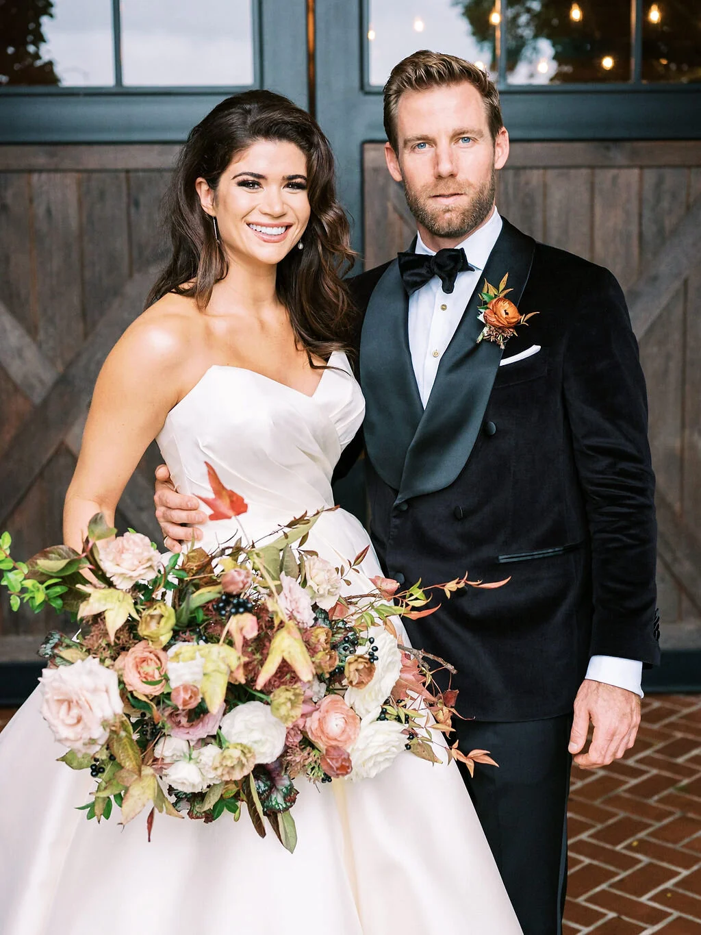 Lush, wild, untamed fall bridal bouquet with a muted autumnal color palette, composed of ligustrum berries, dusty pink ranunculus, tulips, garden roses, fall leaves, begonia leaves, and muted textures. Nashville wedding and corporate event floral de…
