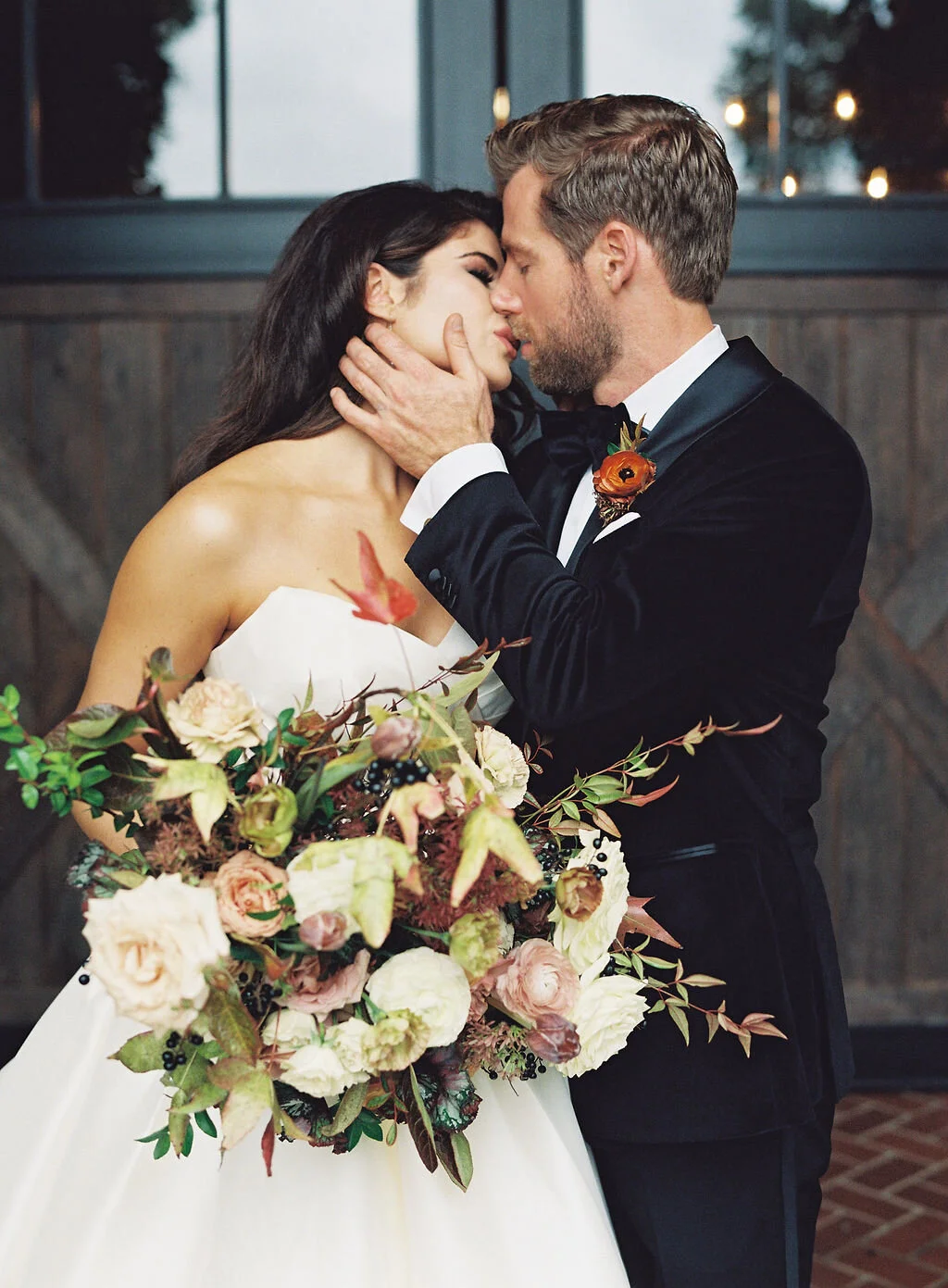 Lush, wild, untamed fall bridal bouquet with a muted autumnal color palette, composed of ligustrum berries, dusty pink ranunculus, tulips, garden roses, fall leaves, begonia leaves, and muted textures. Nashville wedding and corporate event floral de…