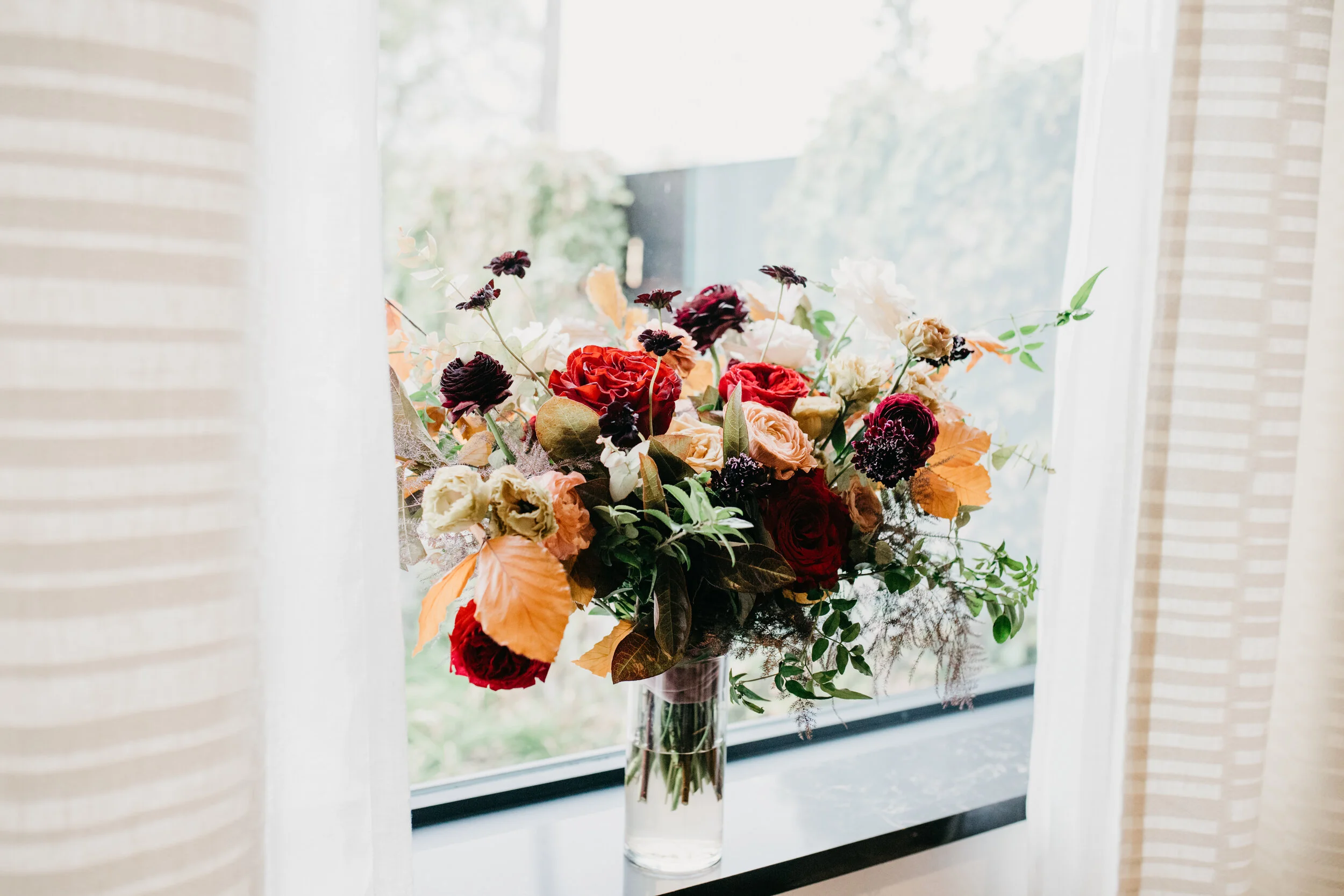 Lush, asymmetrical bridal bouquet with rich fall color palette of deep plum, eggplant, copper, and rusty orange with garden roses, ranunculus, and greenery. Nashville wedding floral designer, Rosemary & Finch, at Clementine.