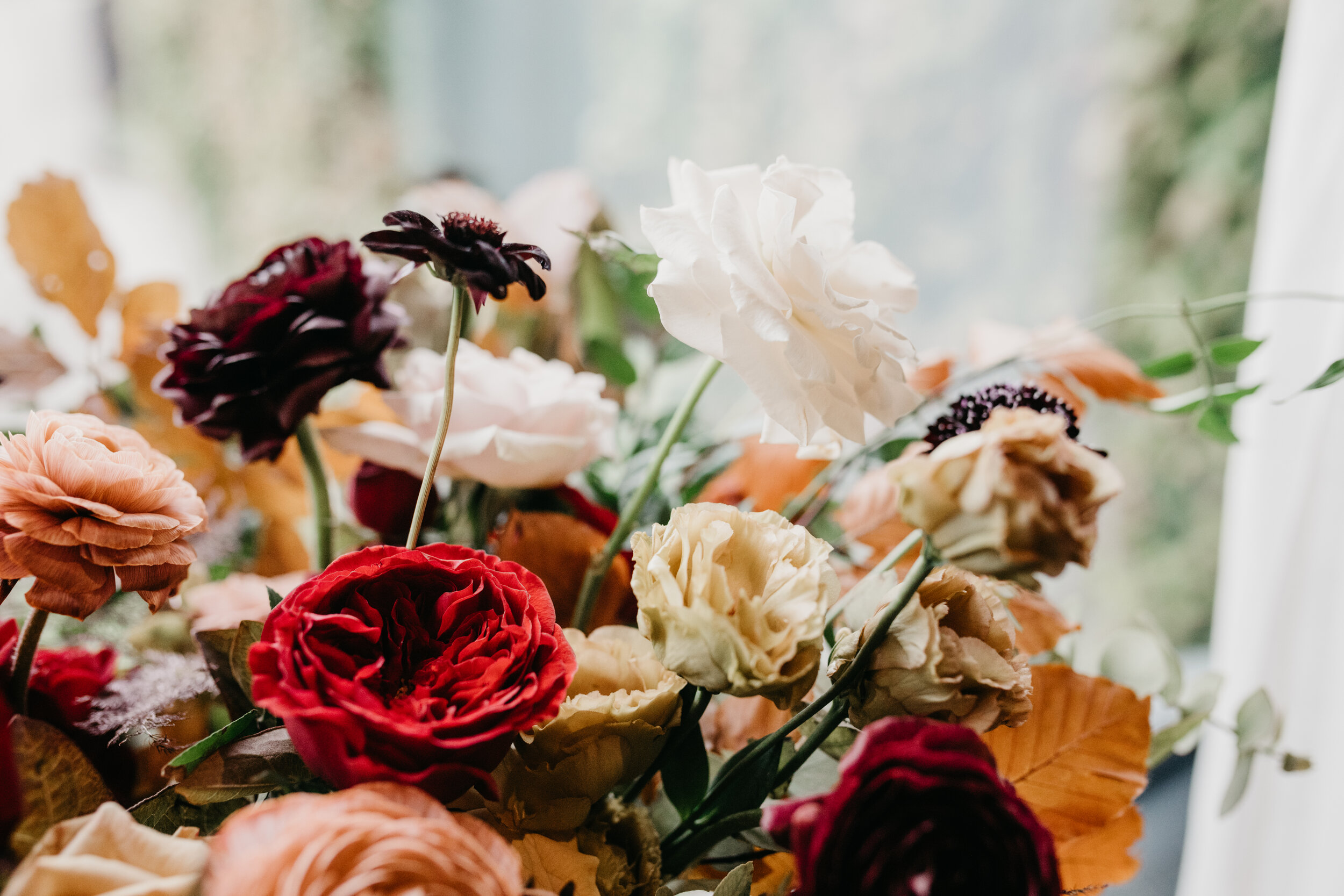 Lush, asymmetrical bridal bouquet with rich fall color palette of deep plum, eggplant, copper, and rusty orange with garden roses, ranunculus, and greenery. Nashville wedding floral designer, Rosemary & Finch, at Clementine.