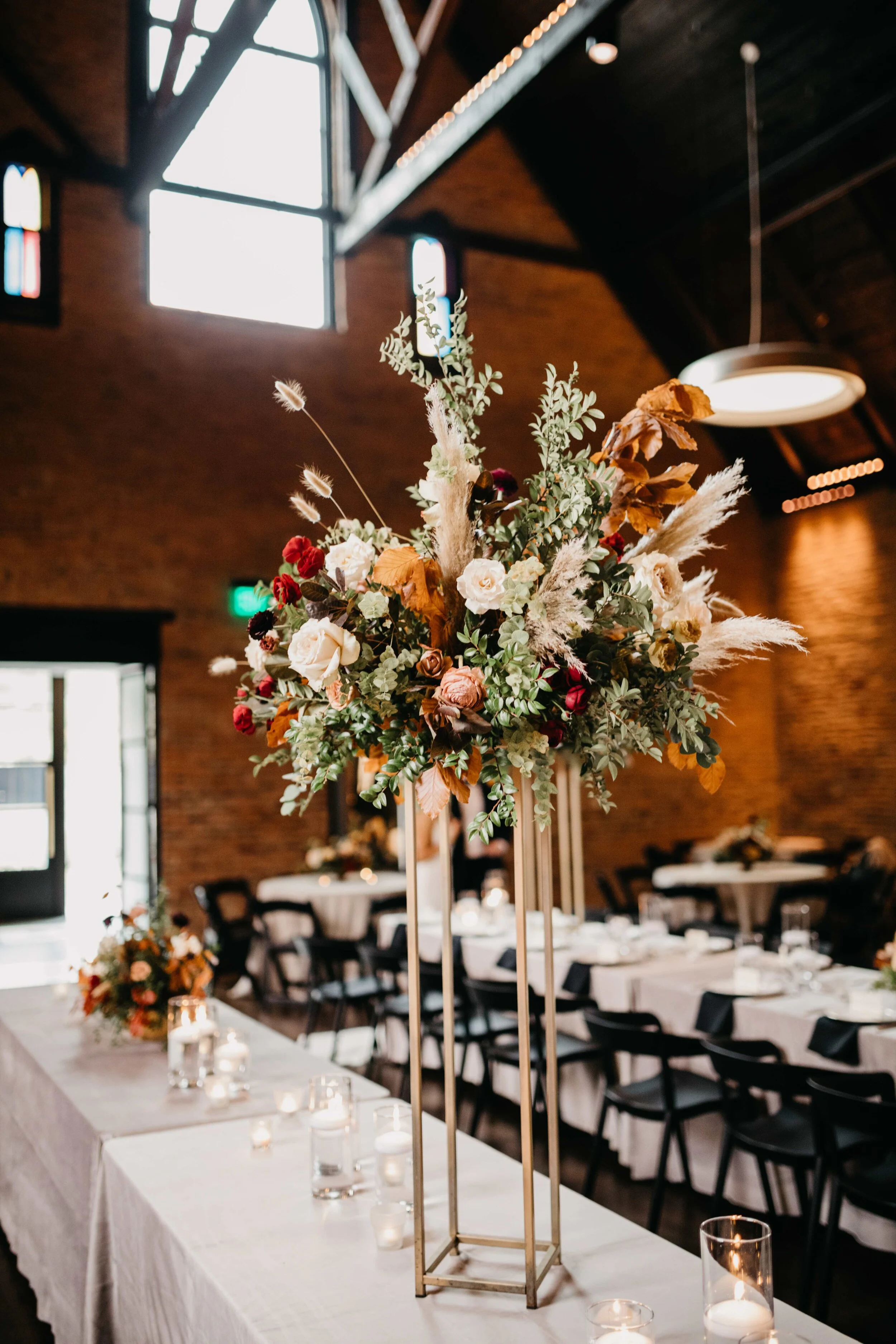 Modern gold stands with lush, asymmetrical floral arrangements using copper beech, pampas grass, garden roses, dahlias, and ranunculus in shades on rusty orange, burgundy, and muted earth tones. Nashville wedding floral design at Clementine.