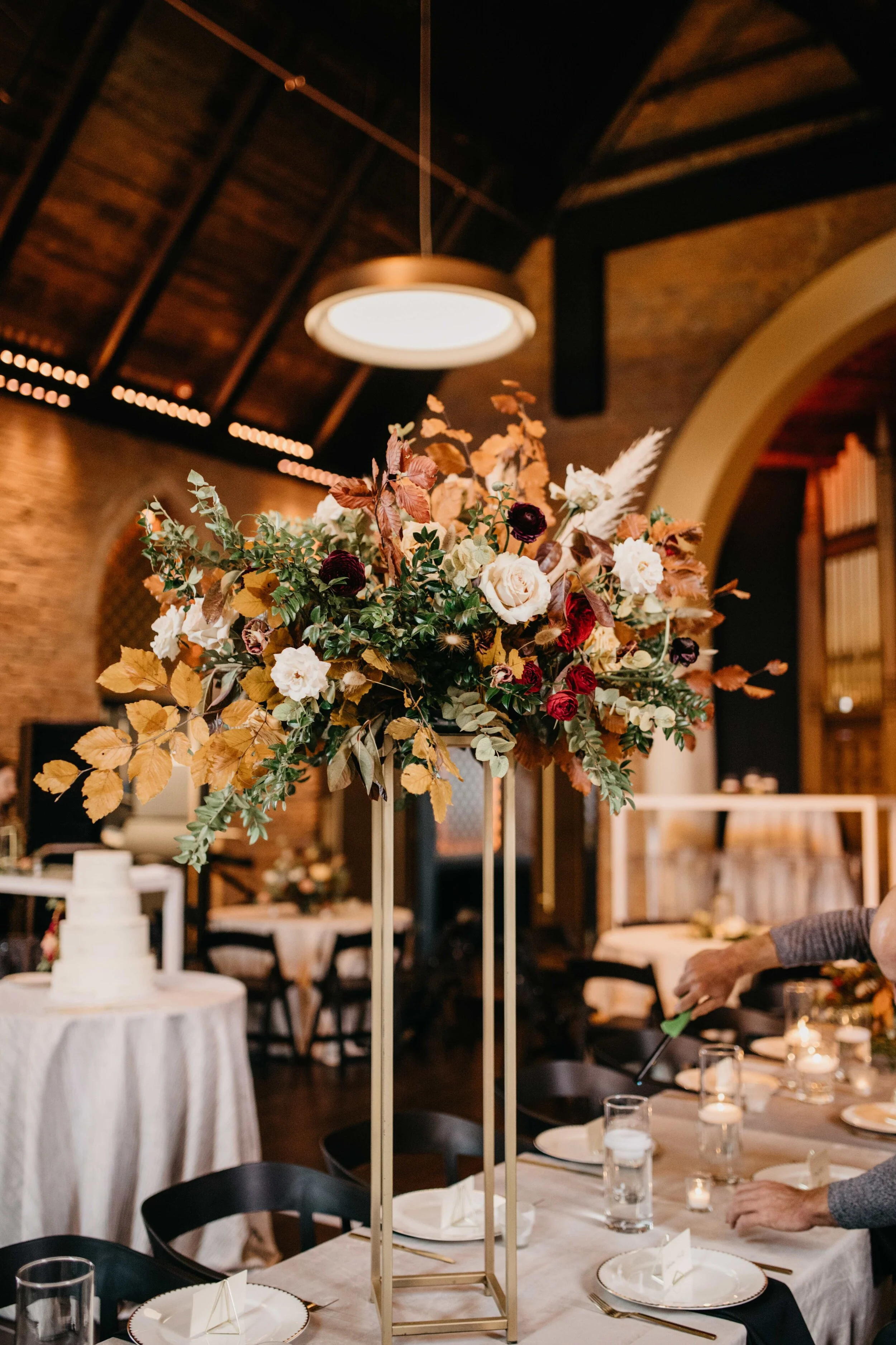Modern gold stand with lush, asymmetrical floral arrangements using copper beech, pampas grass, garden roses, dahlias, and ranunculus in shades on rusty orange, burgundy, and muted earth tones. Nashville wedding floral design at Clementine.