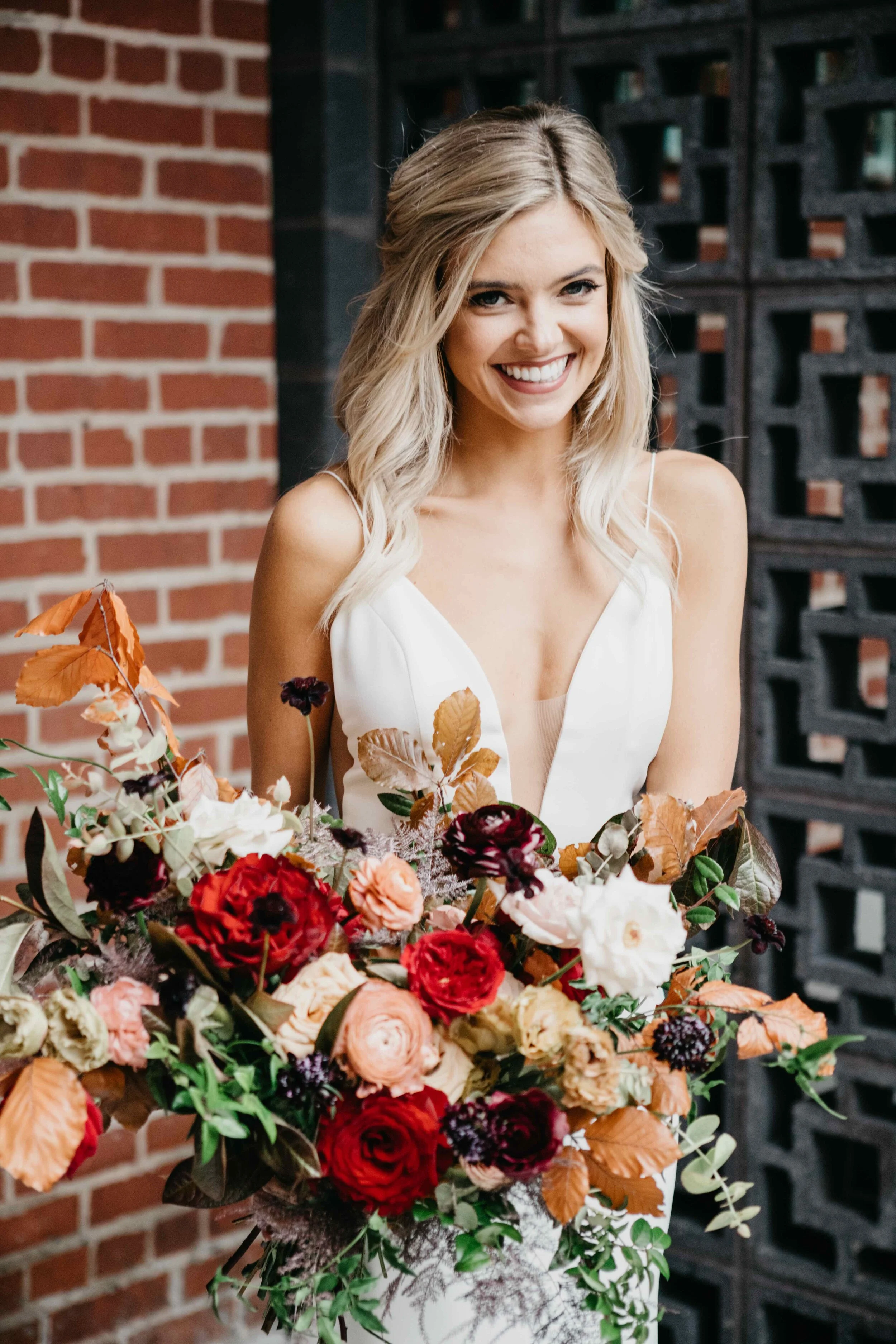 Garden inspired organic bridal bouquet in rich fall color palette using deep red garden roses, eggplant ranunculus, chocolate cosmos, copper beech, dusty rose ranunculus, and natural greenery. Luxury wedding florist in Nashville, TN.