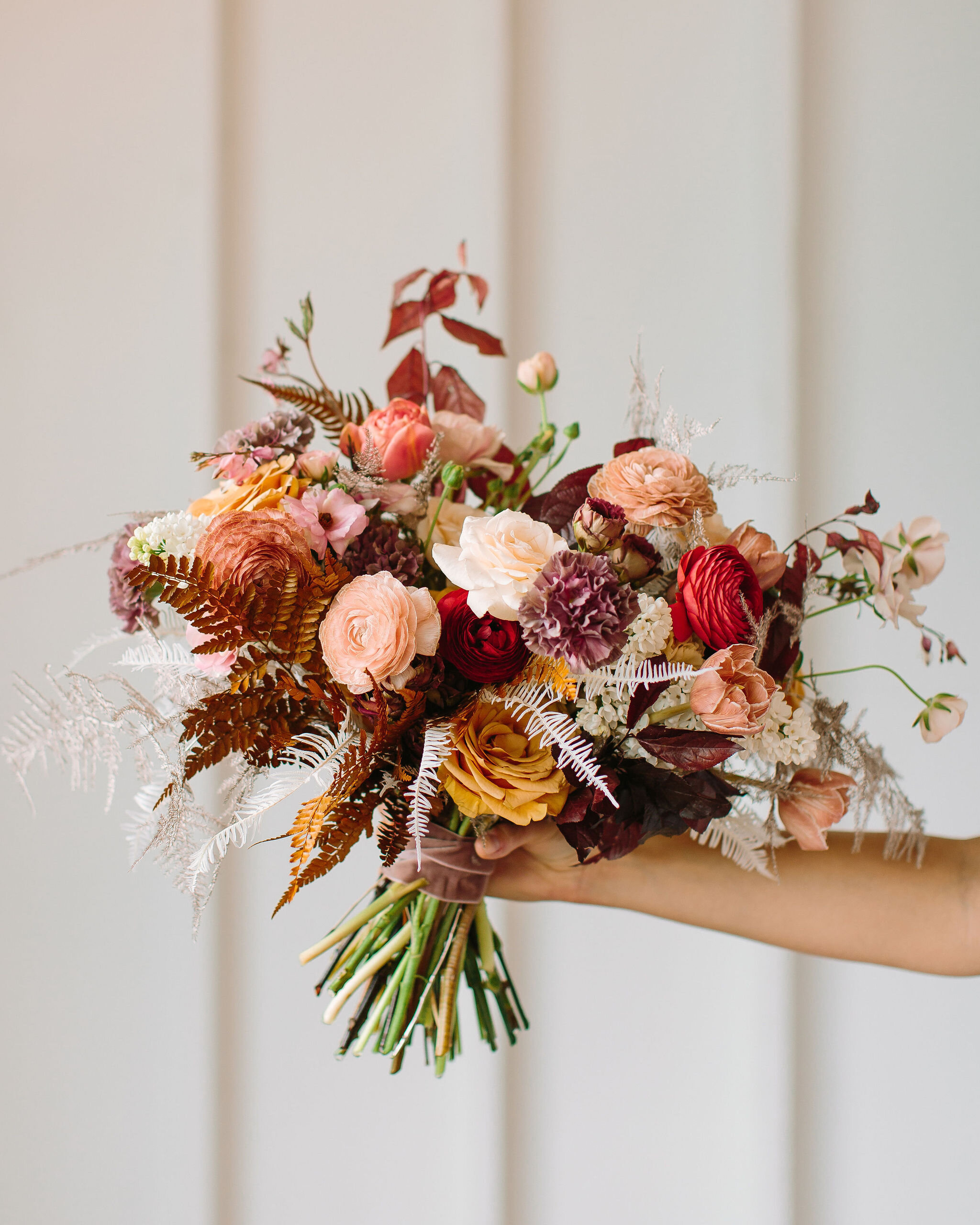 Organic, modern bouquet with dried white ferns, dusty pink ranunculus, golden brown ferns, spirea, bleeding hearts, and other dainty spring flowers. Nashville wedding and event floral design by Rosemary & Finch at 14Tenn.