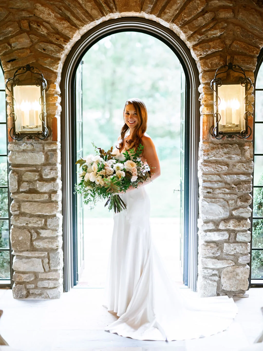 Organic, garden inspired bride’s bouquet with white garden roses, dahlias, and ranunculus with trailing vines and greenery. Nashville wedding floral design.