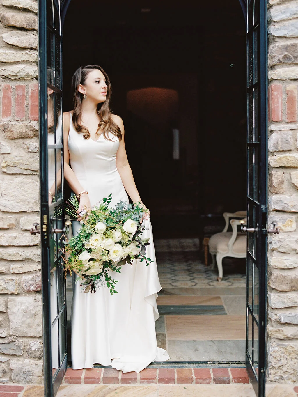 Organic, garden inspired bride’s bouquet with white garden roses, dahlias, and ranunculus with trailing vines and greenery. Nashville wedding floral design.