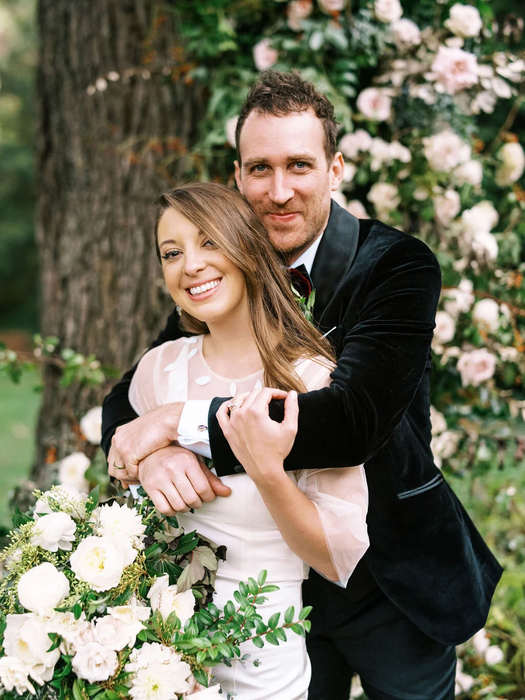 Lush floral installation on an old oak tree with natural vines and greenery with a profusion of white, ivory, and blush garden roses, dahlias, ranunculus, and wildflowers. Belle Meade, Nashville wedding floral design.