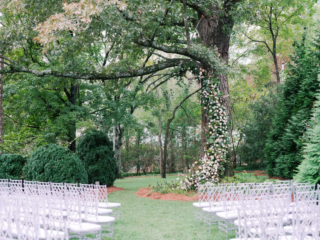 Lush floral installation on an old oak tree with natural vines and greenery with a profusion of white, ivory, and blush garden roses, dahlias, ranunculus, and wildflowers. Belle Meade, Nashville wedding floral design.
