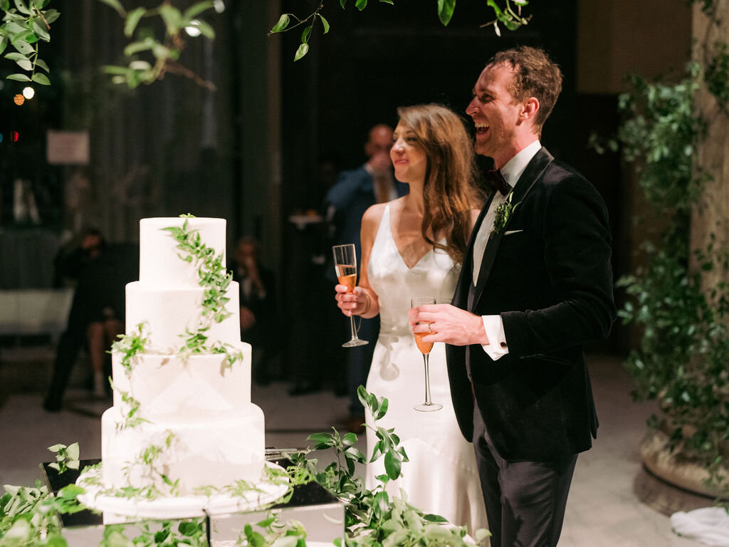 Dramatic cake table setting with lush vine and greenery installation hanging and delicate jasmine vines on the cake. Nashville wedding floral design at the Parthenon.