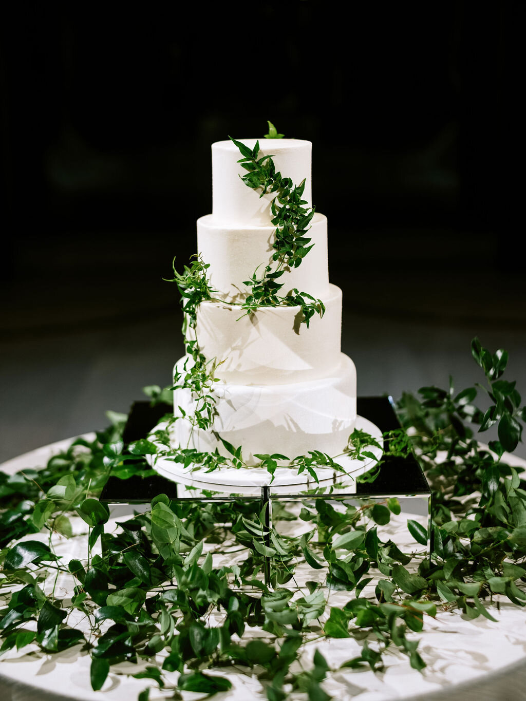 Dramatic cake table setting with lush vine and greenery installation hanging and delicate jasmine vines on the cake. Nashville wedding floral design at the Parthenon.