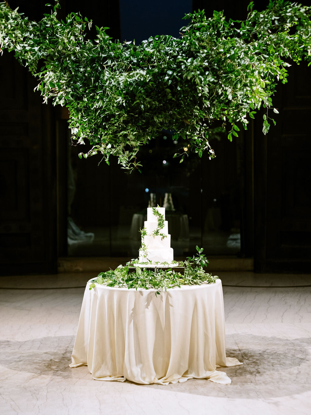 Dramatic cake table setting with lush vine and greenery installation hanging and delicate jasmine vines on the cake. Nashville wedding floral design at the Parthenon.