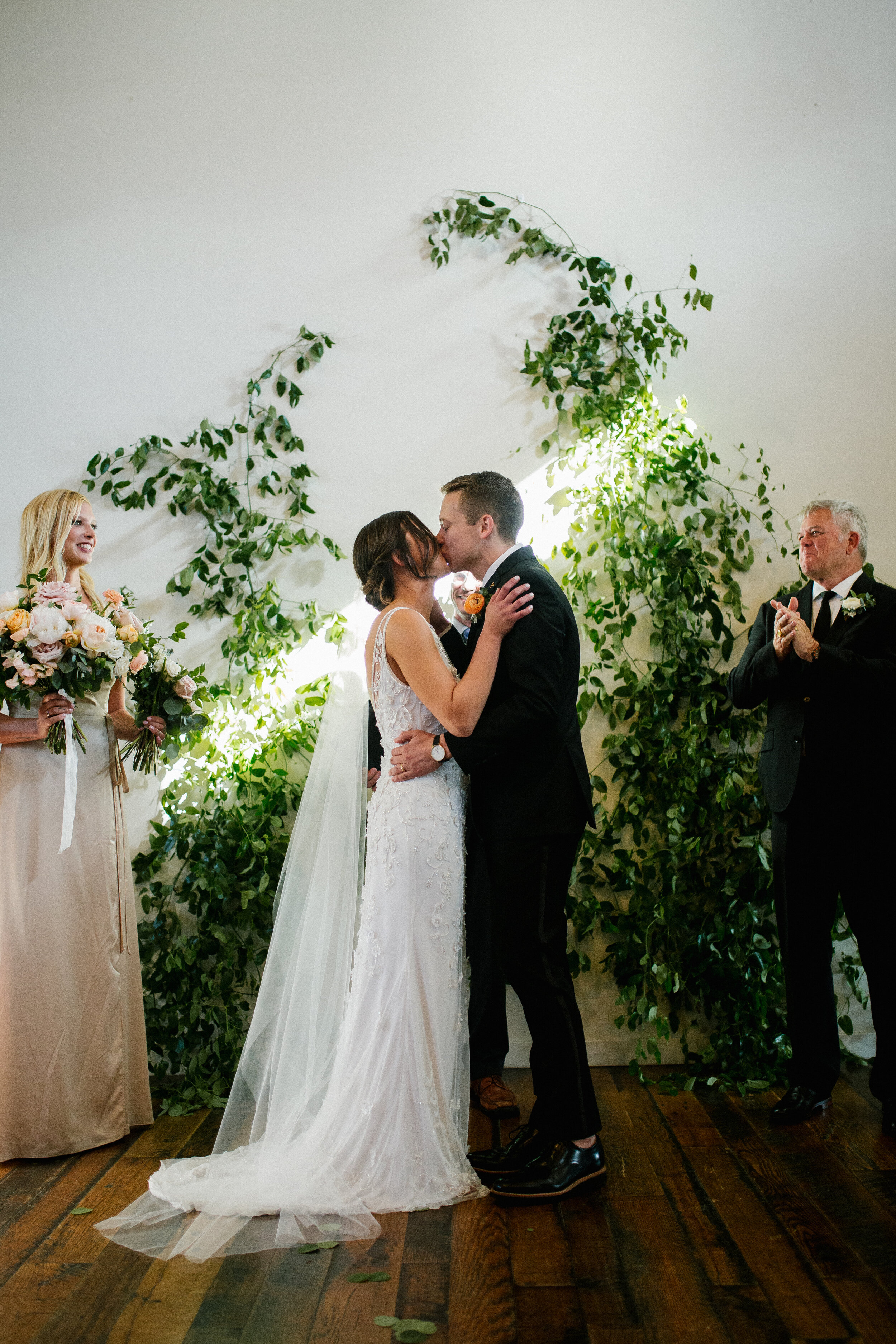 Vine-like greenery installation - creating an arch on the white wall at the Cordelle as the wedding ceremony backdrop. Nashville wedding floral design.