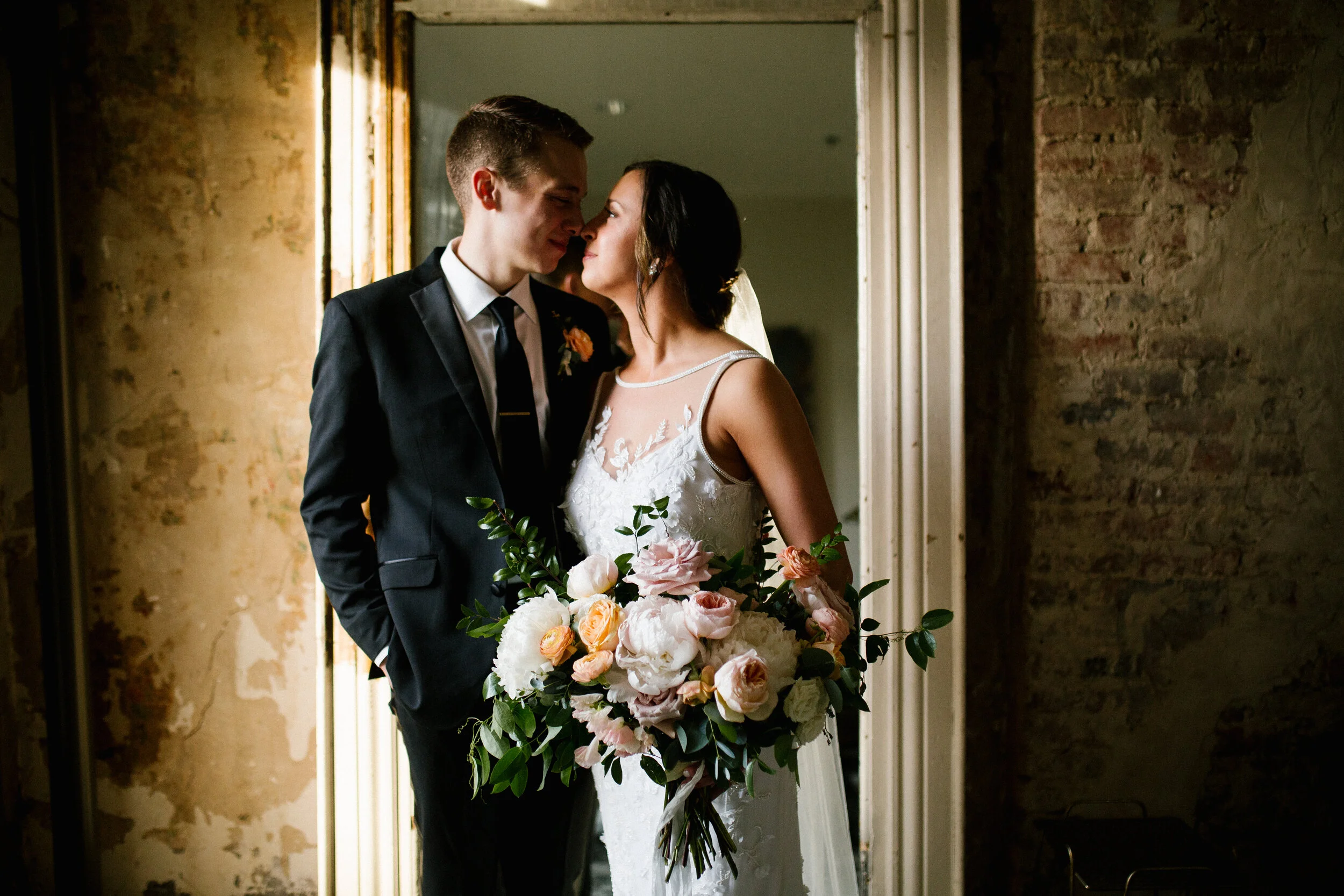 Bridal bouquet with peach ranunculus, cream peonies, blush and golden yellow garden roses, and natural, untamed greenery. June wedding at the Cordelle. Nashville Wedding Florist.