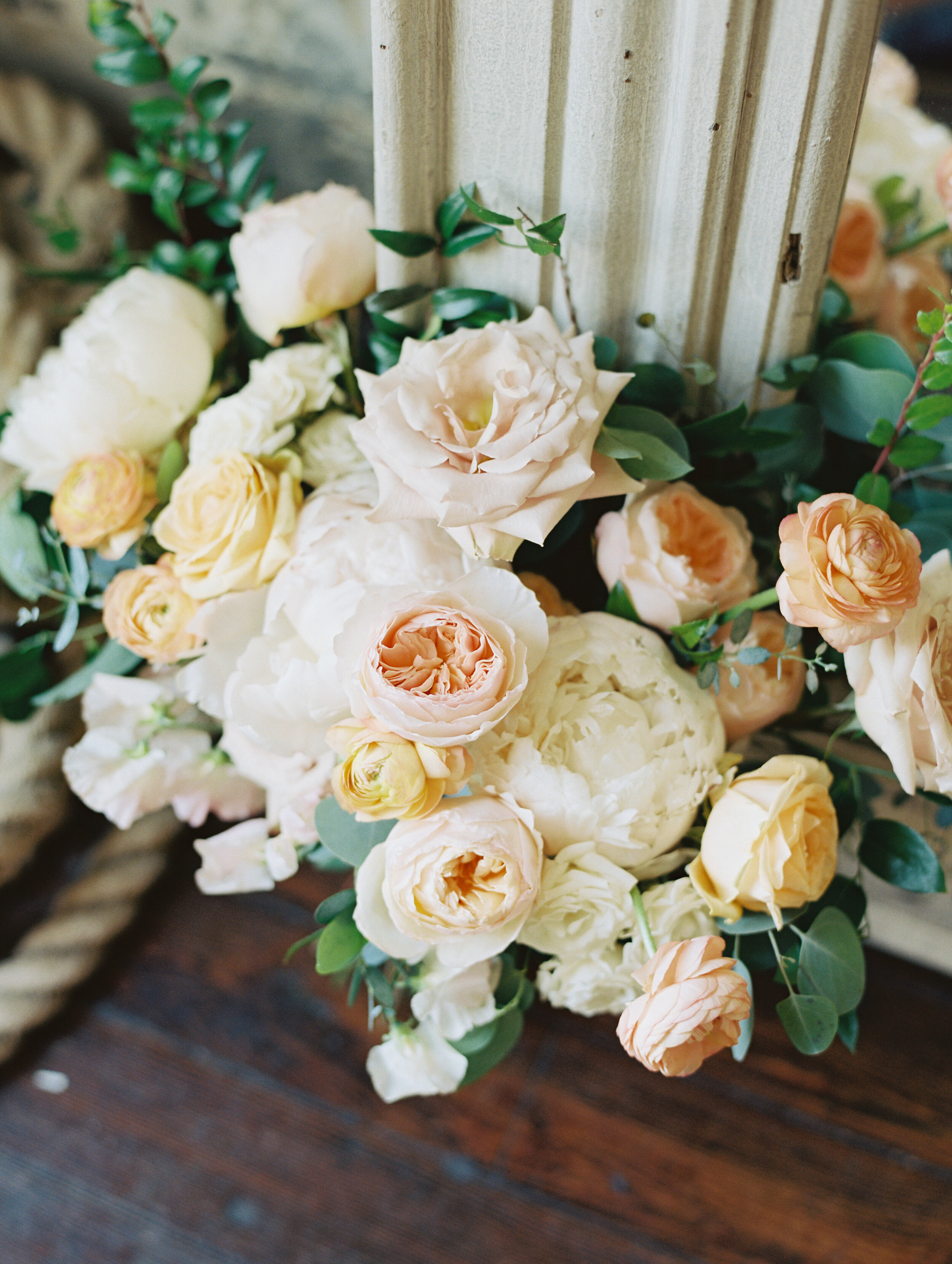 Bridal bouquet with peach ranunculus, cream peonies, blush and golden yellow garden roses, and natural, untamed greenery. June wedding at the Cordelle. Nashville Wedding Florist.