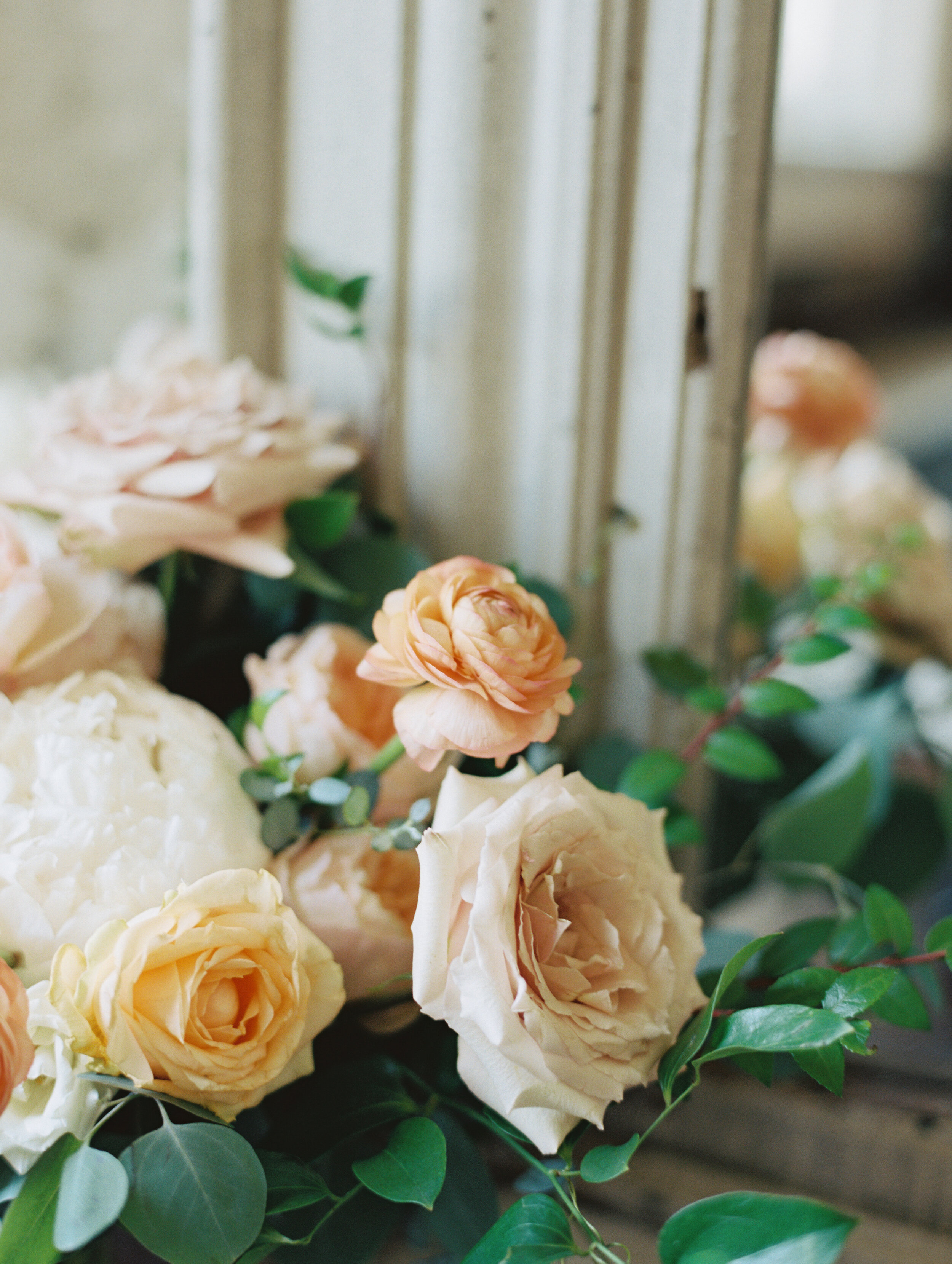 Bridal bouquet with peach ranunculus, cream peonies, blush and golden yellow garden roses, and natural, untamed greenery. June wedding at the Cordelle. Nashville Wedding Florist.