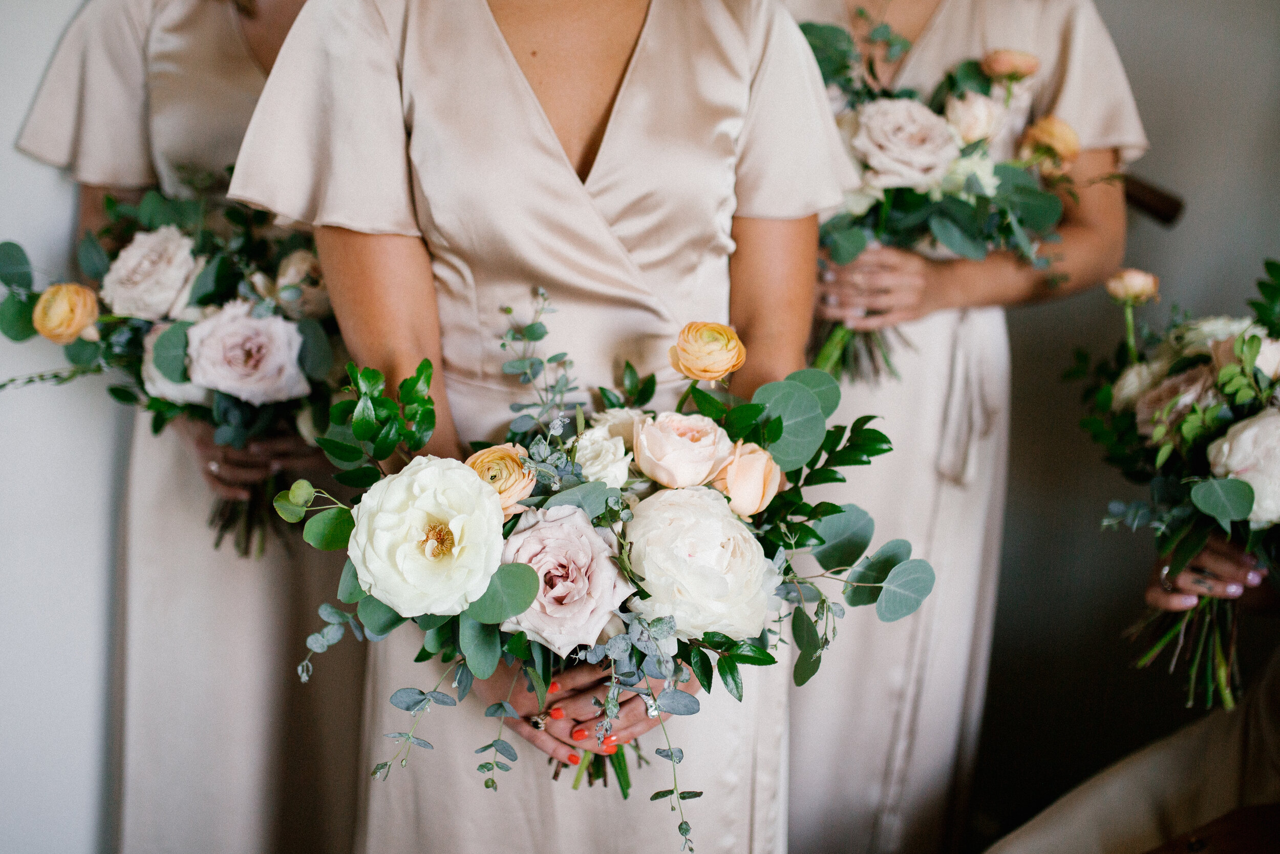 Lush, garden-inspired bouquets with peach, white, and dusty rose flowers and natural greenery. Champagne silk bridesmaid dresses. Nashville wedding florist.