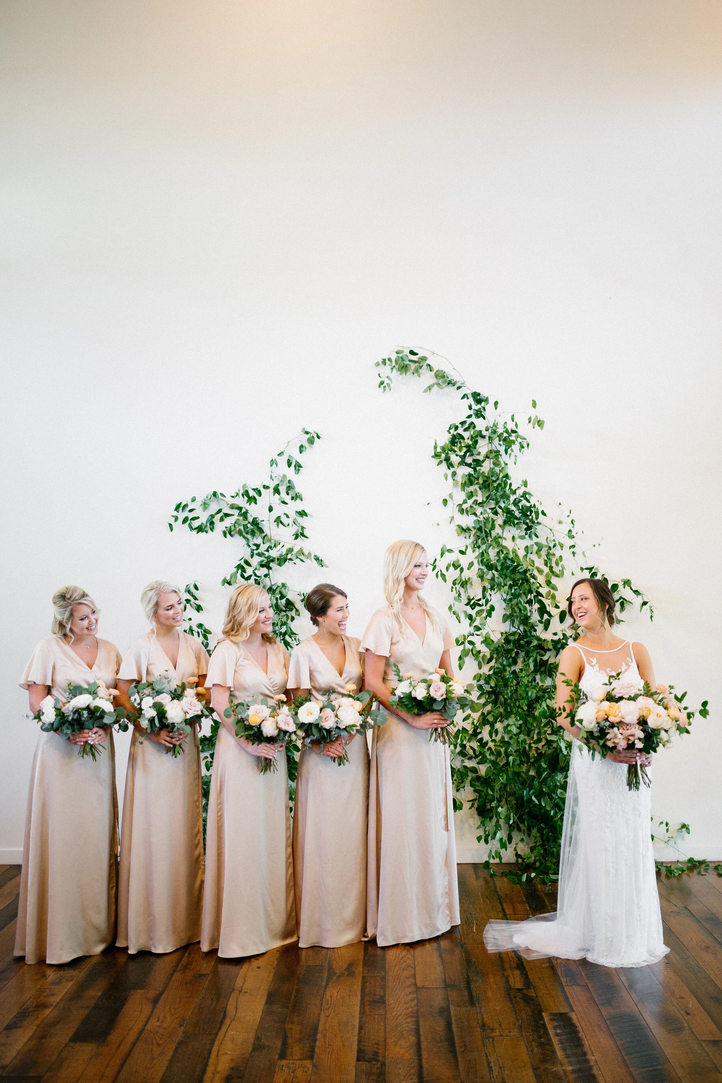 Lush, garden-inspired bouquets with peach, white, and dusty rose flowers and natural greenery. Champagne silk bridesmaid dresses. Nashville wedding florist.
