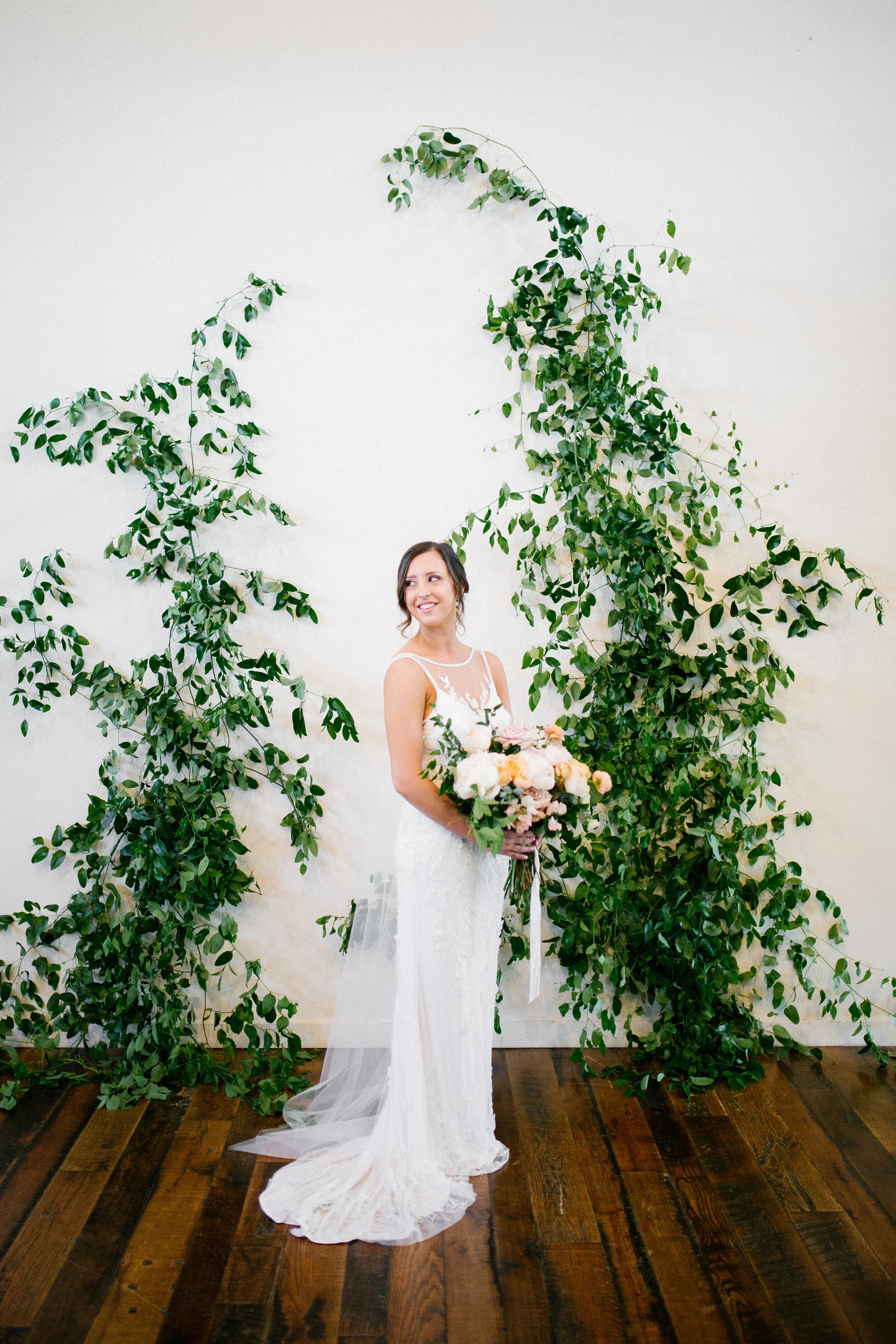 Vine-like greenery installation - creating an arch on the white wall at the Cordelle as the wedding ceremony backdrop. Nashville wedding floral design.