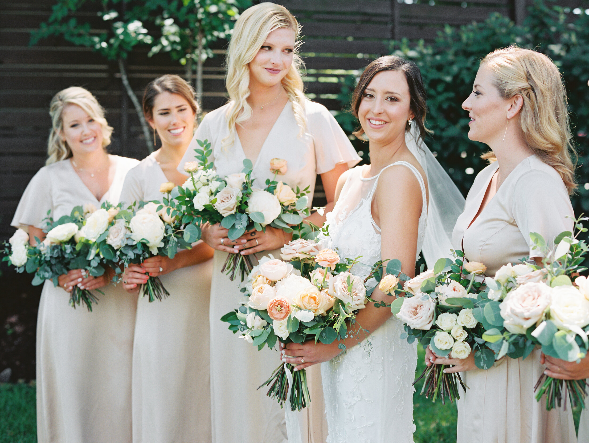 Lush, garden-inspired bouquets with peach, white, and dusty rose flowers and natural greenery. Champagne silk bridesmaid dresses. Nashville wedding florist.