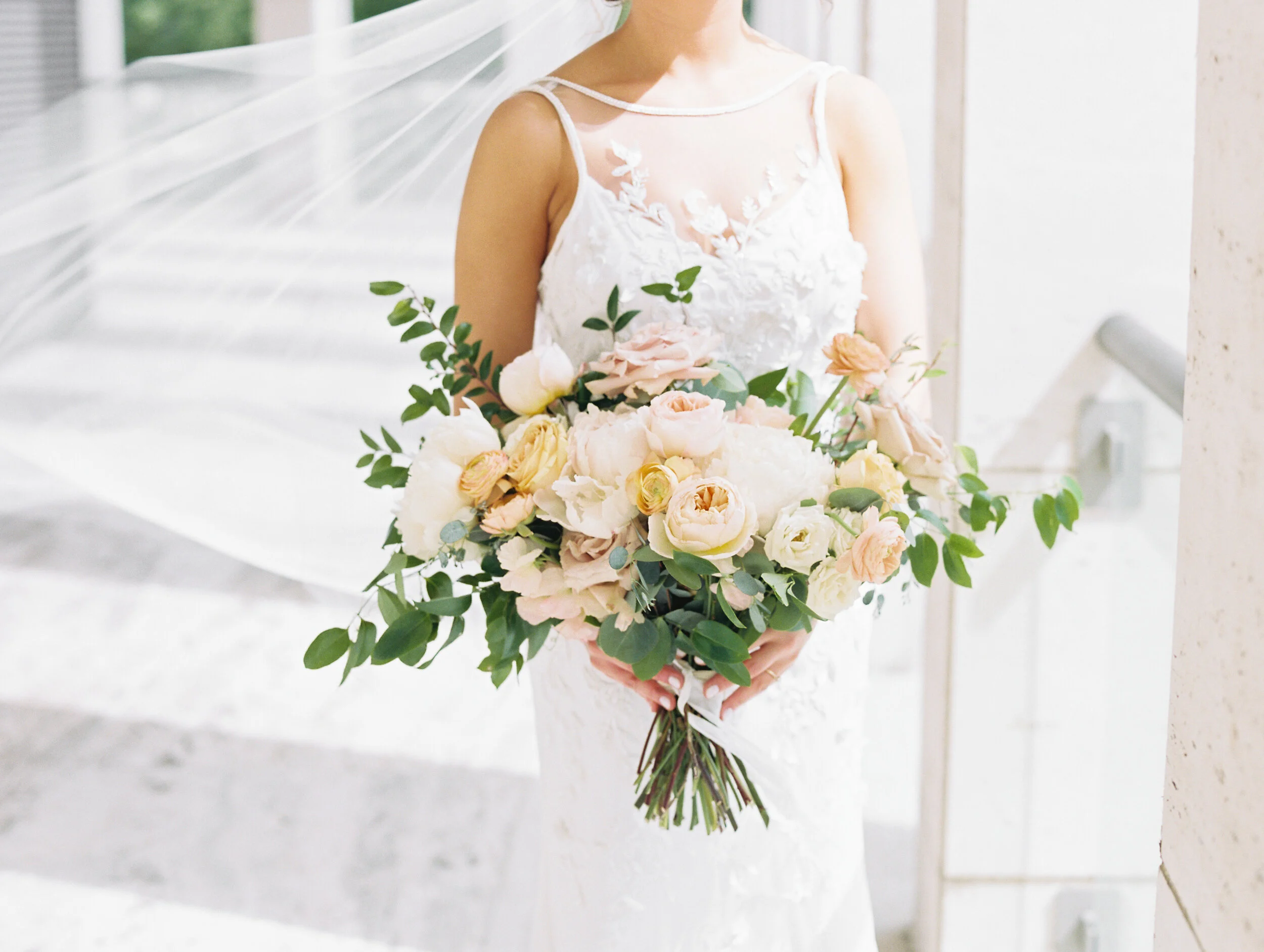 Bridal bouquet with peach ranunculus, cream peonies, blush and golden yellow garden roses, and natural, untamed greenery. June wedding at the Cordelle. Nashville Wedding Florist.