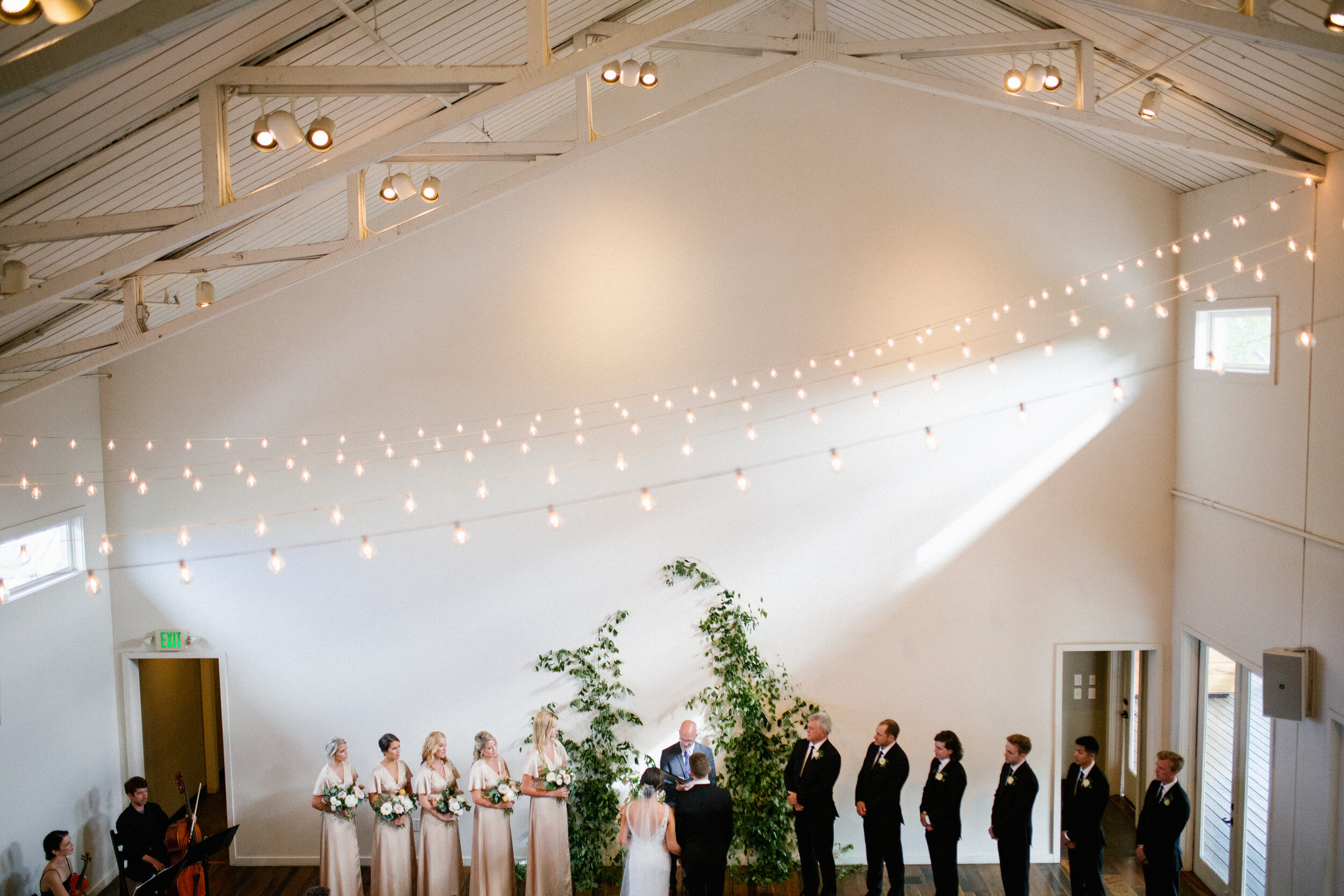 Vine-like greenery installation - creating an arch on the white wall at the Cordelle as the wedding ceremony backdrop. Nashville wedding floral design.