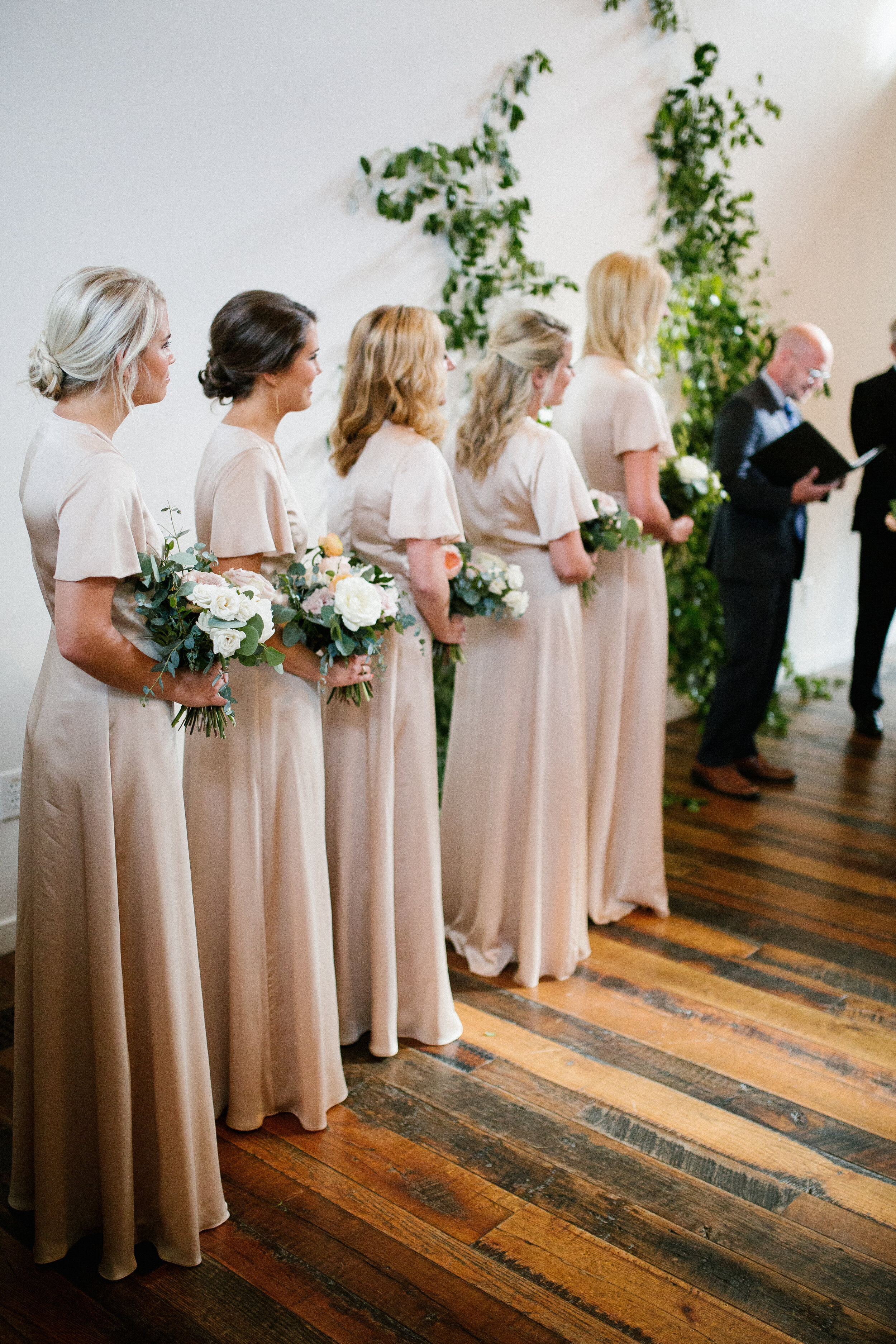 Lush, garden-inspired bouquets with peach, white, and dusty rose flowers and natural greenery. Champagne silk bridesmaid dresses. Nashville wedding florist.