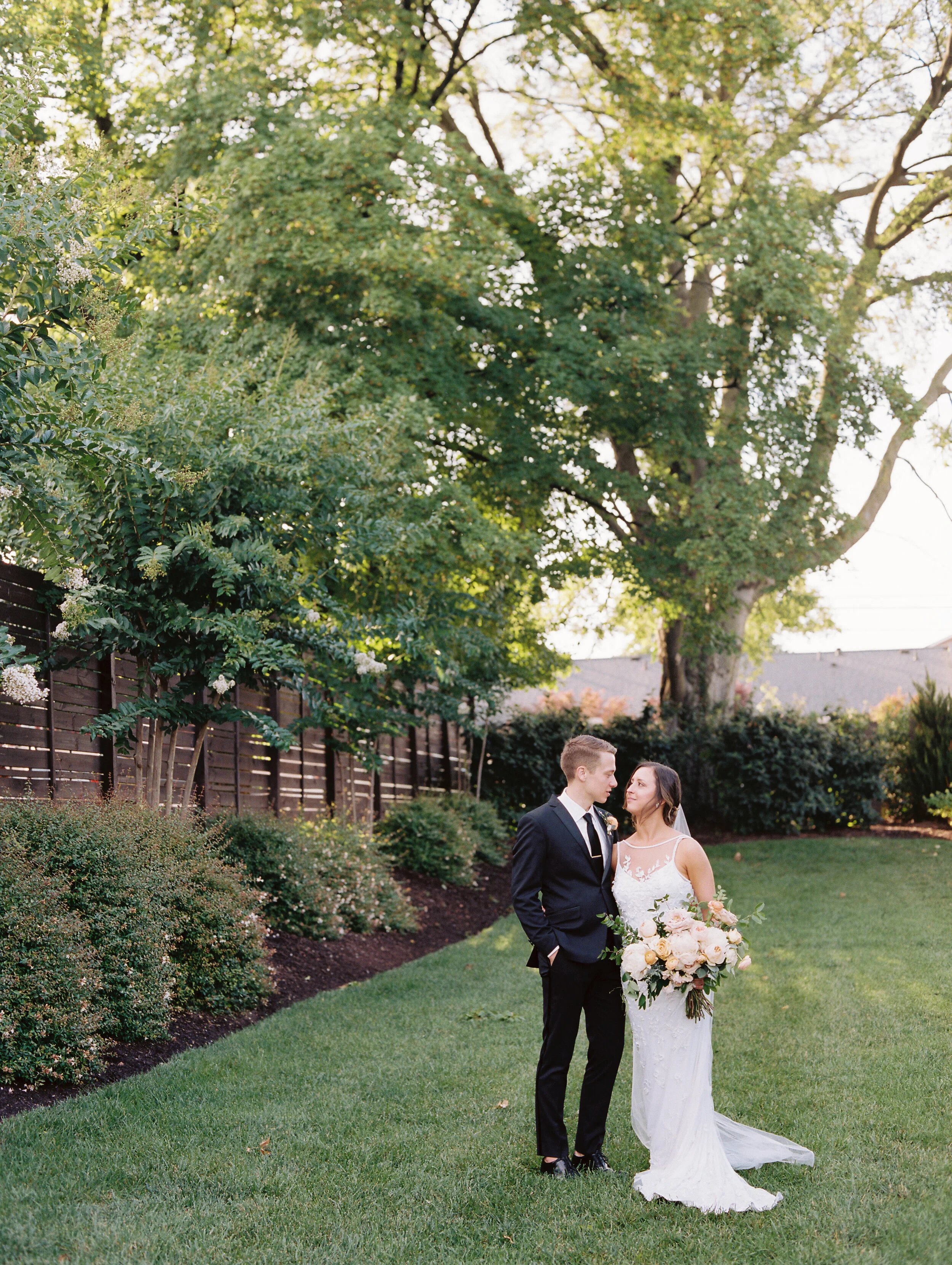 Bridal bouquet with peach ranunculus, cream peonies, blush and golden yellow garden roses, and natural, untamed greenery. June wedding at the Cordelle. Nashville Wedding Florist.