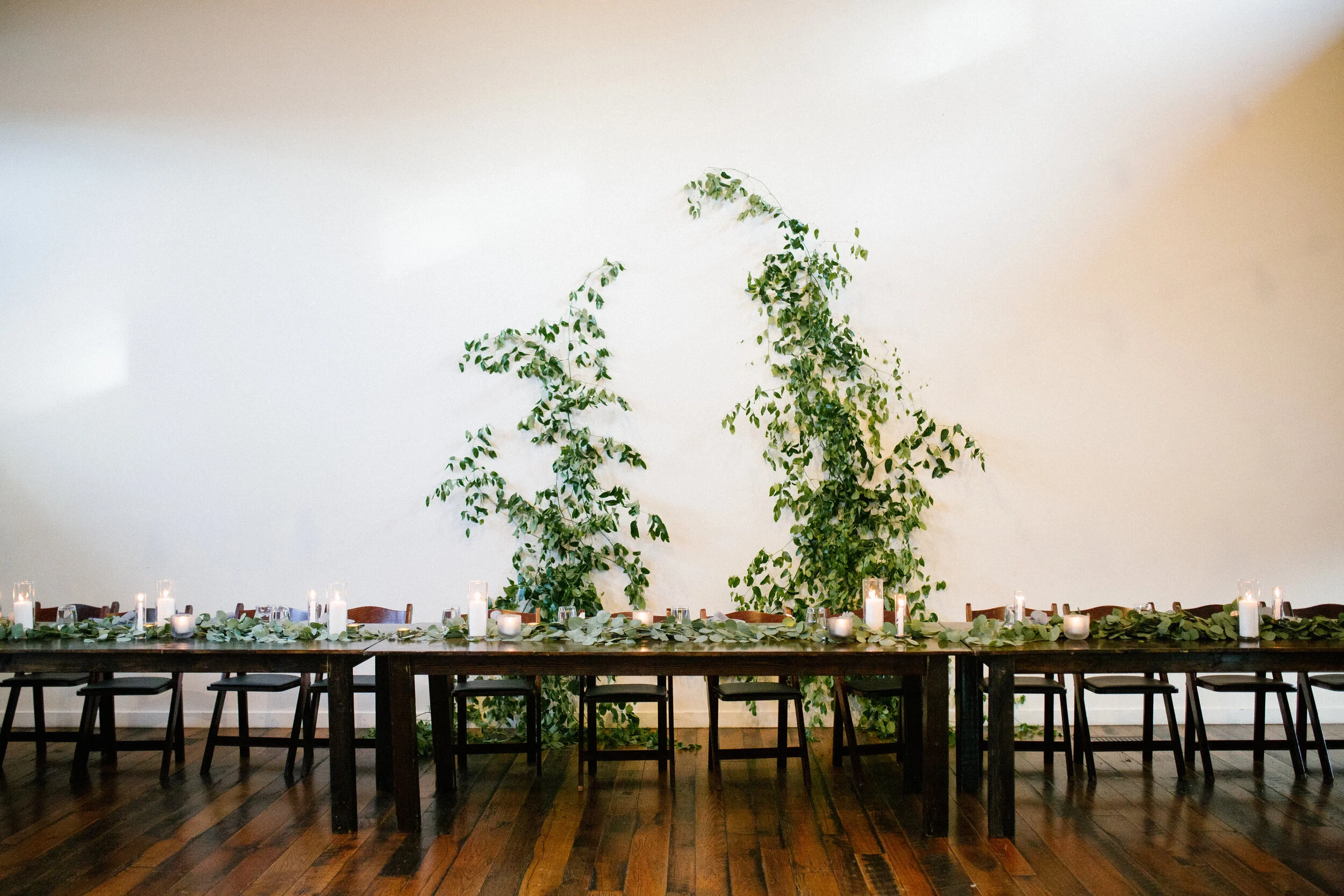 Vine-like greenery installation - creating an arch on the white wall at the Cordelle as the wedding ceremony backdrop. Nashville wedding floral design.