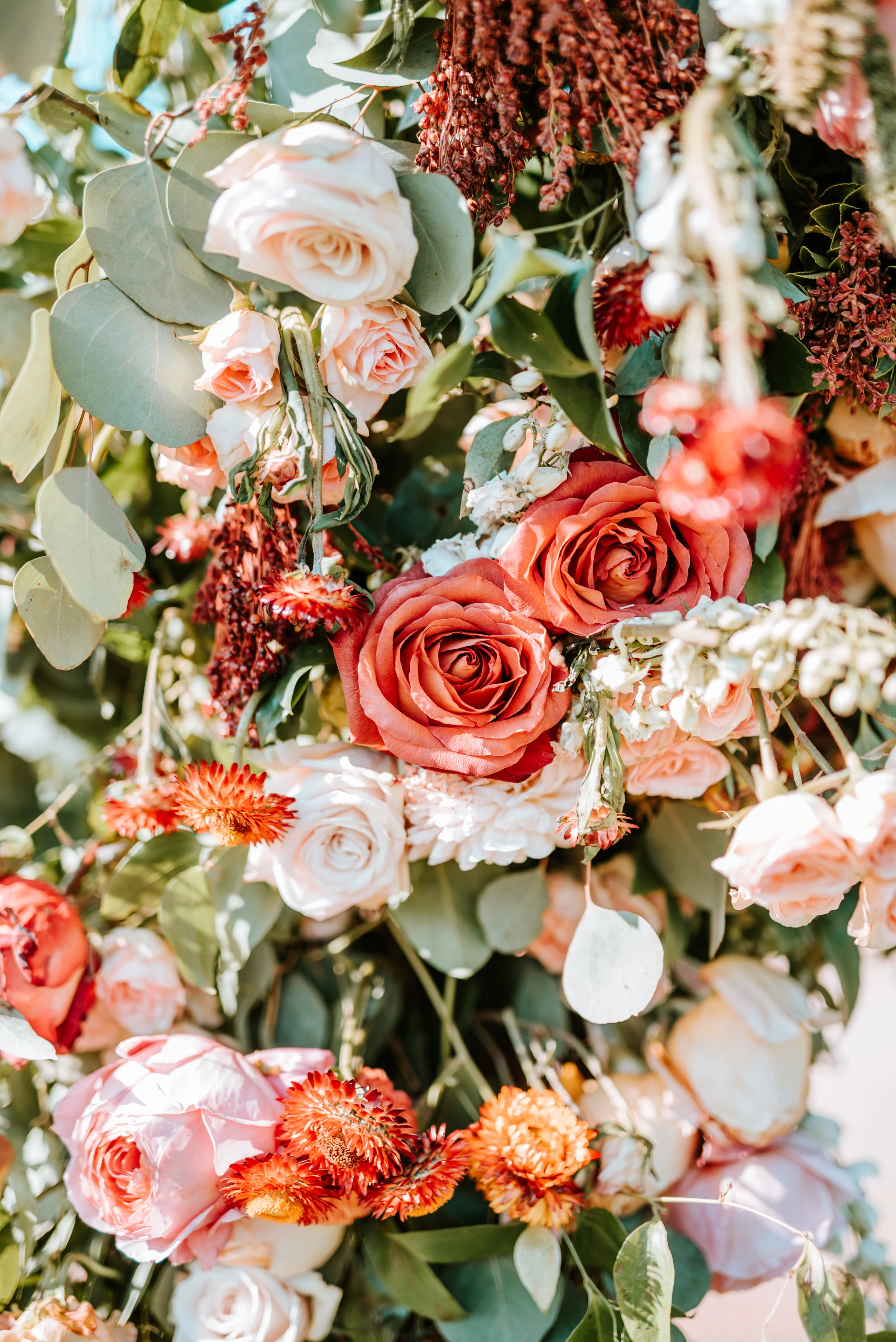 Lush floral arch for a fall wedding at Long Hollow Gardens with untamed greenery, berries, and rust orange garden roses.