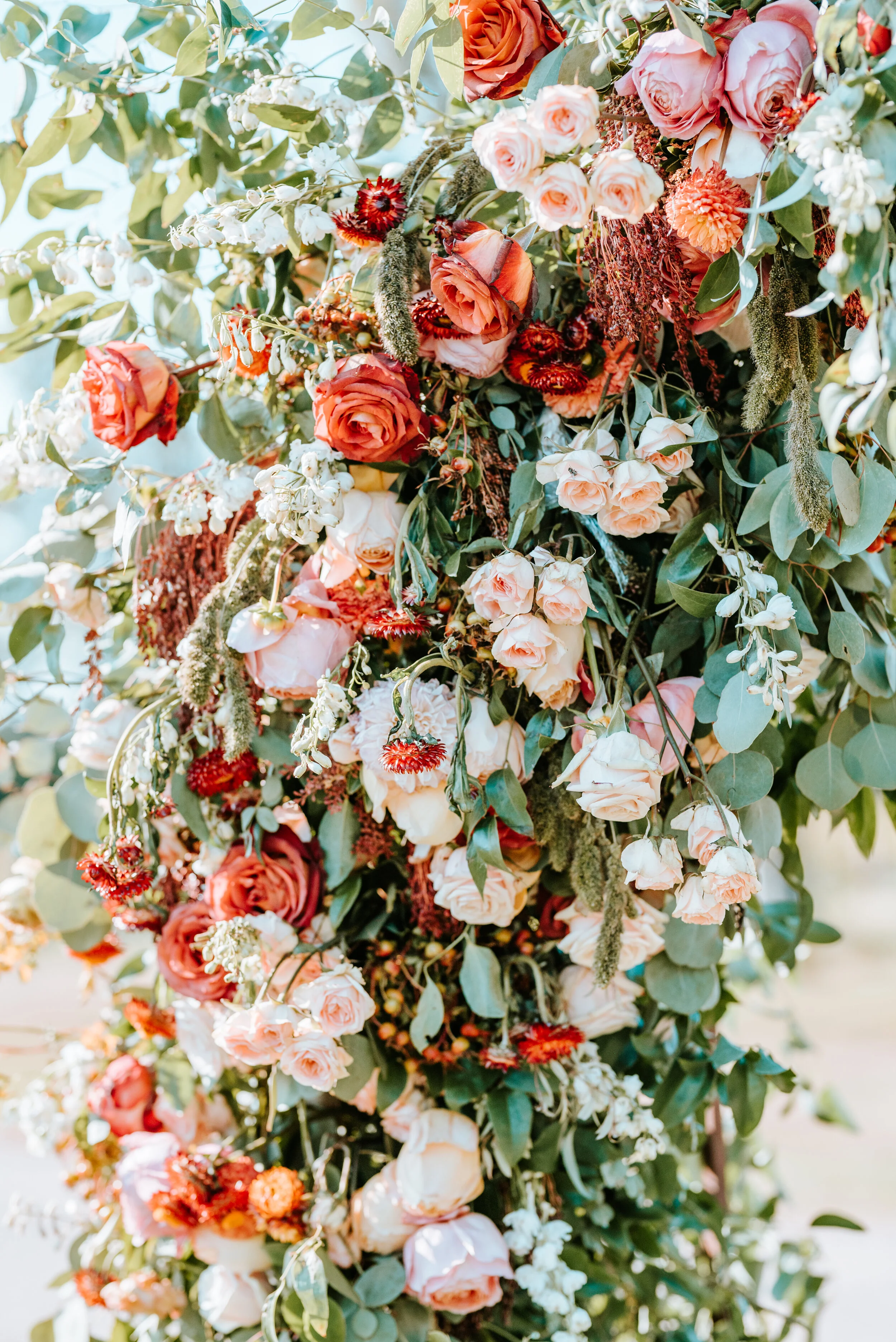 Lush floral arch for a fall wedding at Long Hollow Gardens with untamed greenery, berries, and rust orange garden roses.