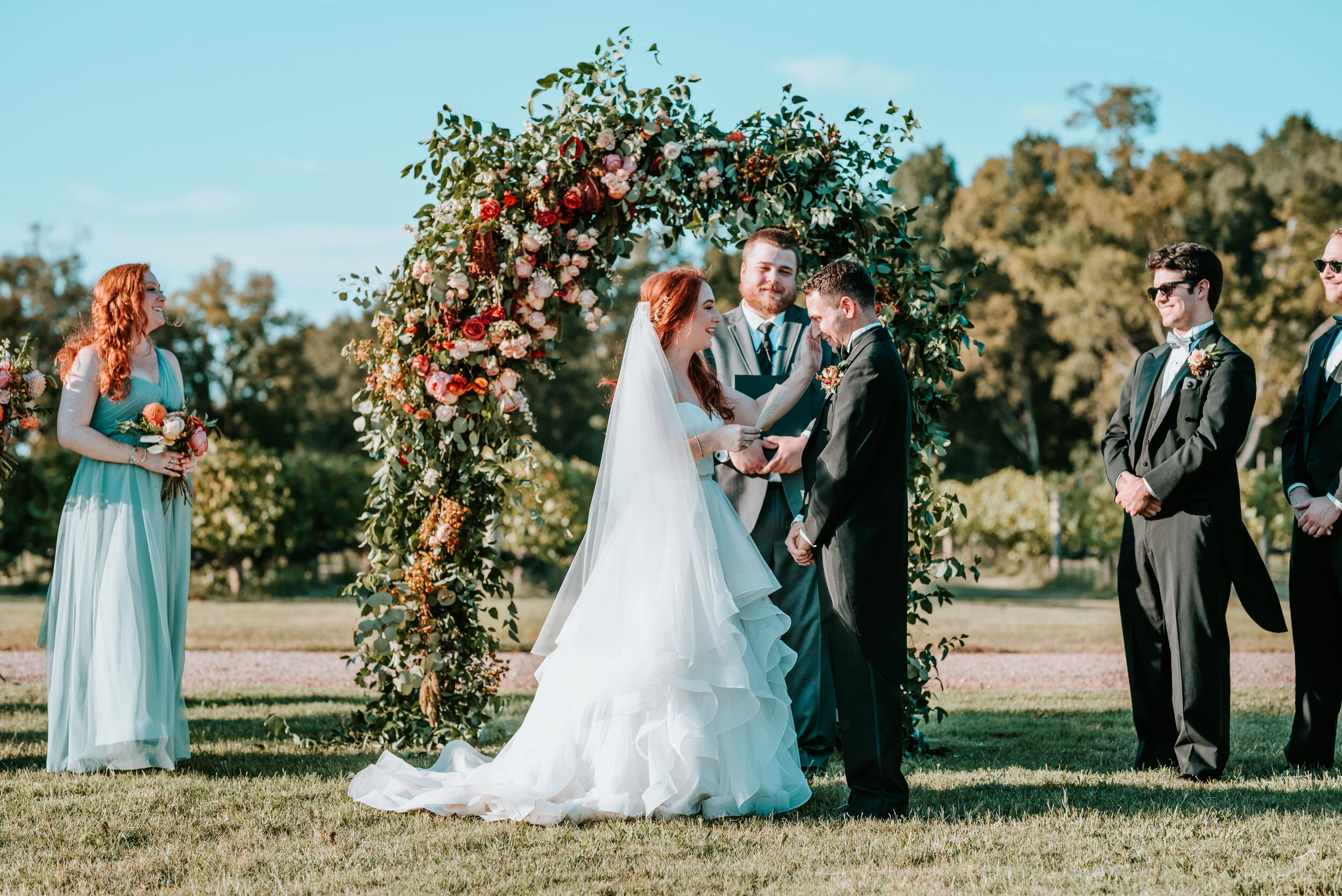 Lush floral arch for a fall wedding at Long Hollow Gardens with untamed greenery, berries, and rust orange garden roses.